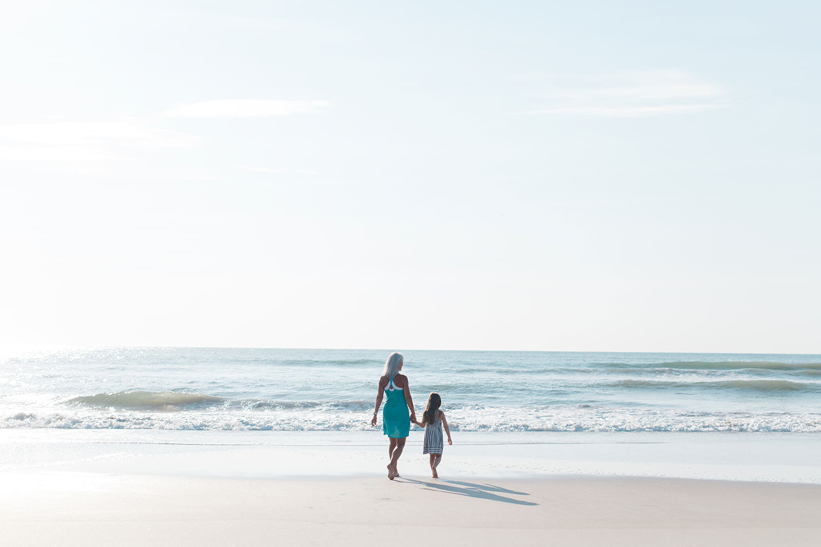 Florida beach family photographer photographs family on the beach walking towards the ocean