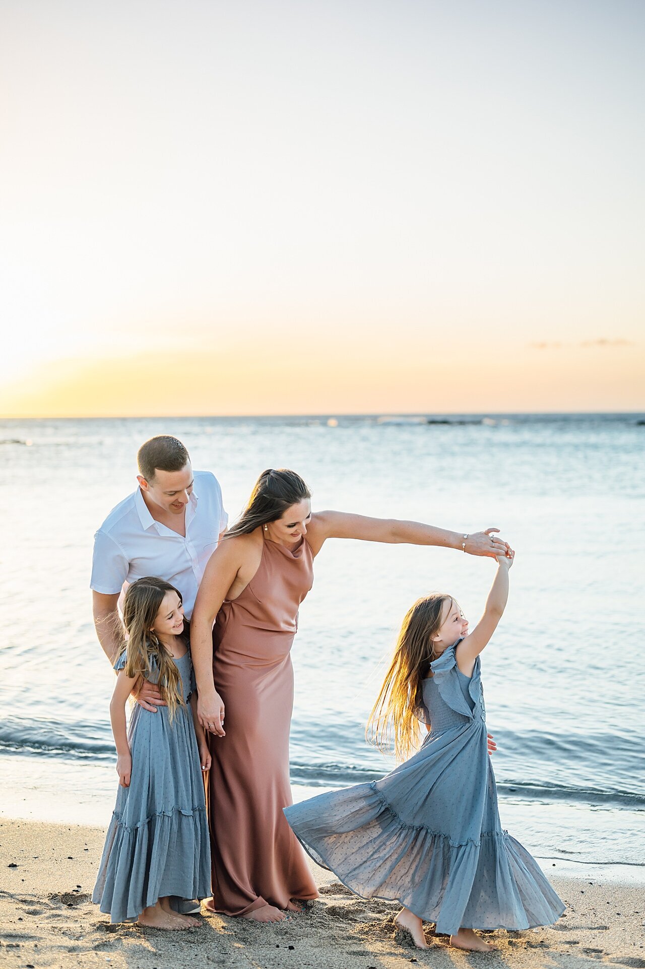girl twirling with family at the beach in hawaii