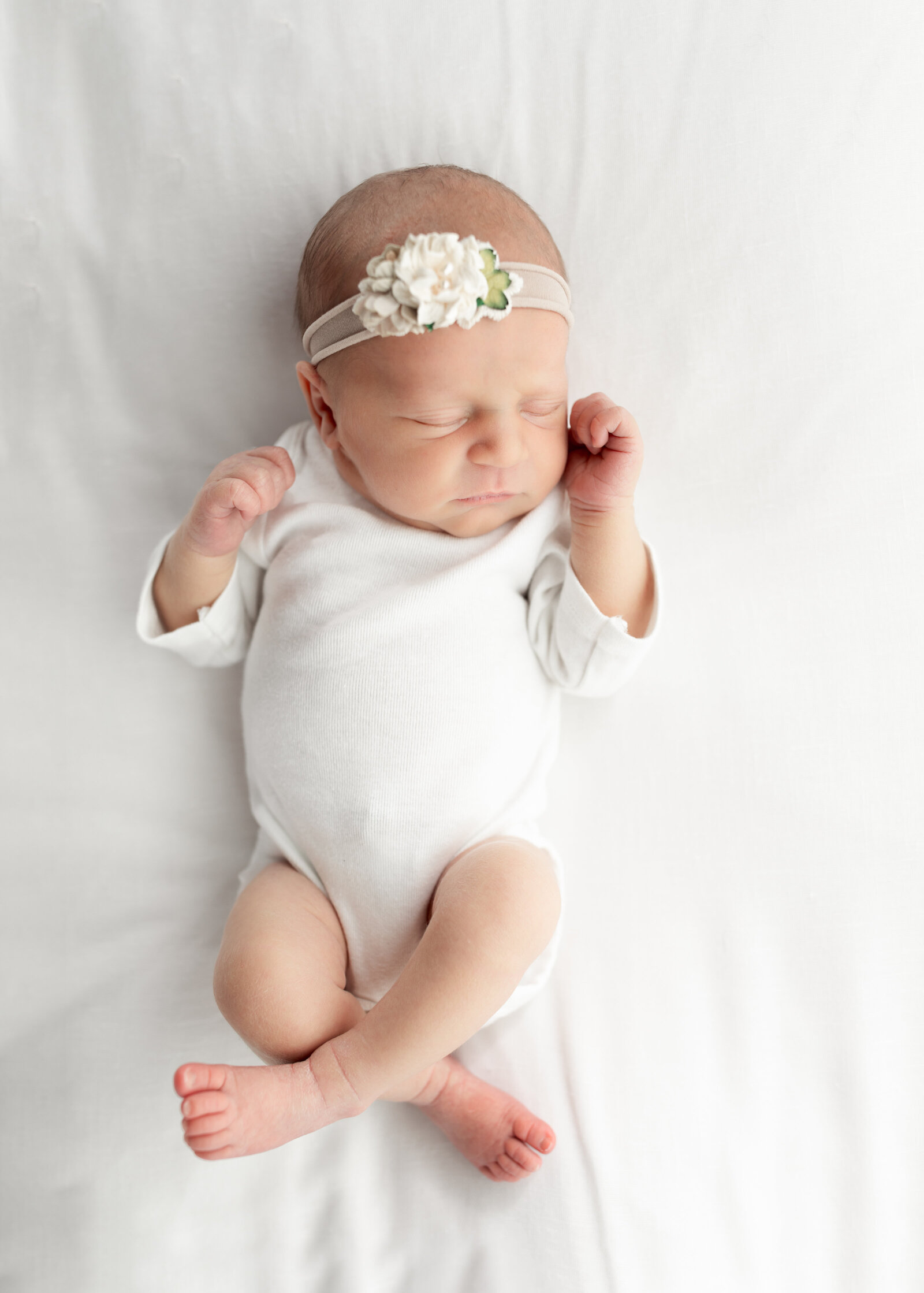 newborn baby girl in posed on white fabric for newborn studio photography