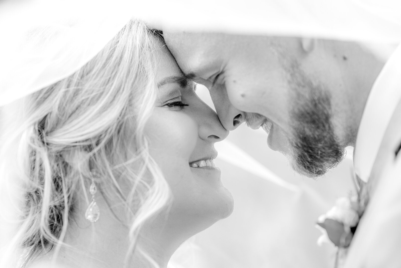 Bride and groom nose-to-nose under veil- black and white