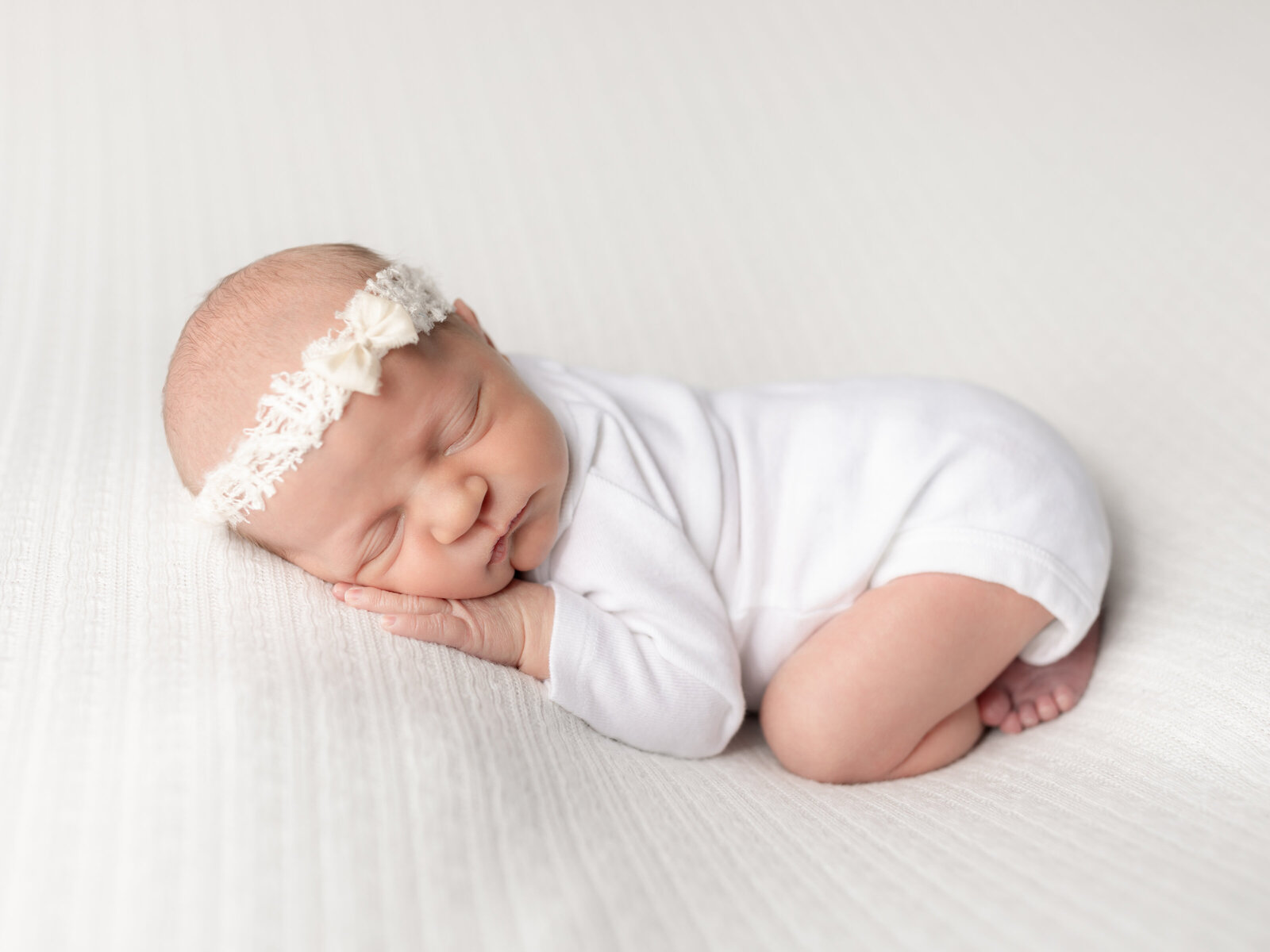 newborn baby posed on white fabric for studio portraits