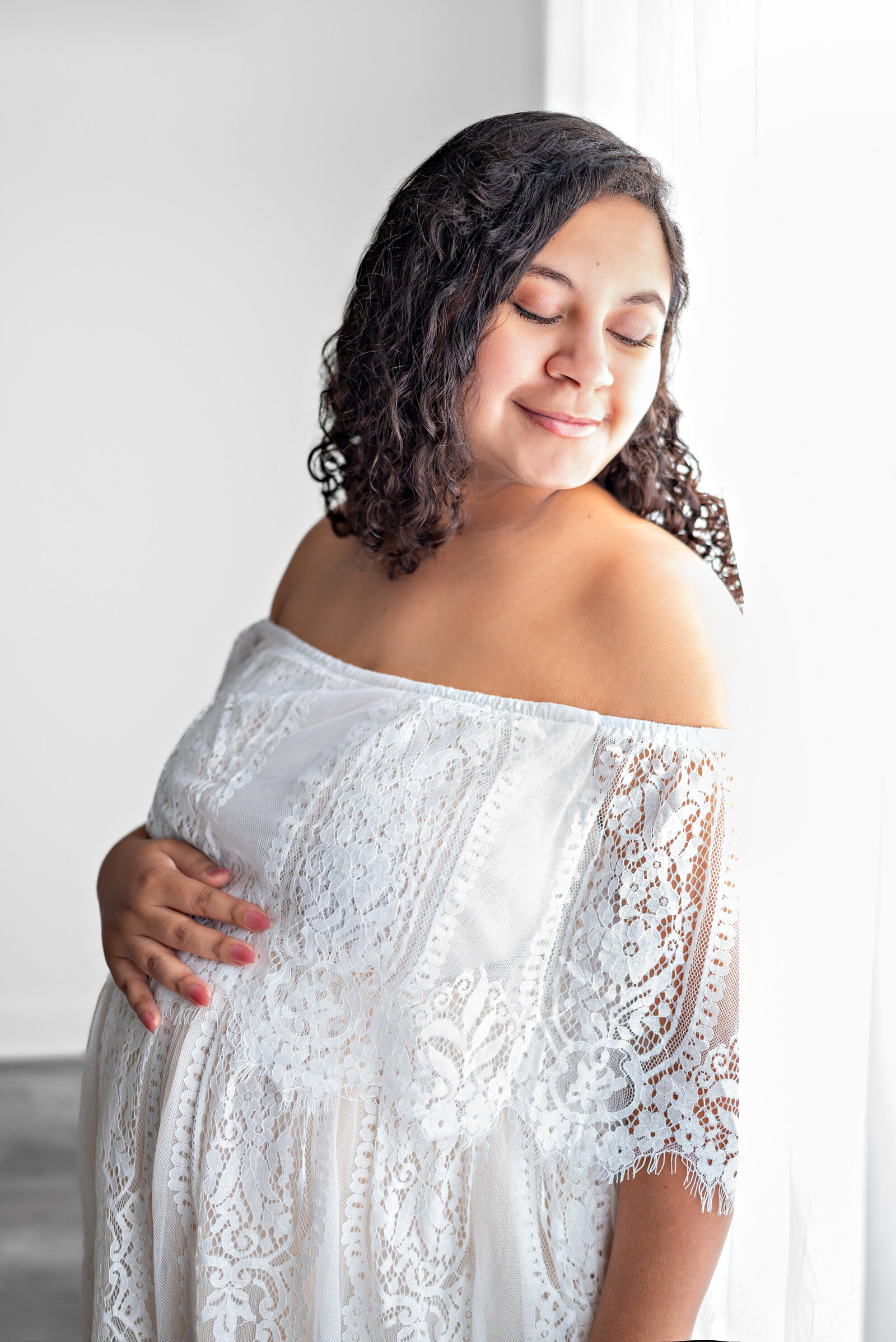 mother caressing her stomach as she poses for her maternity photos
