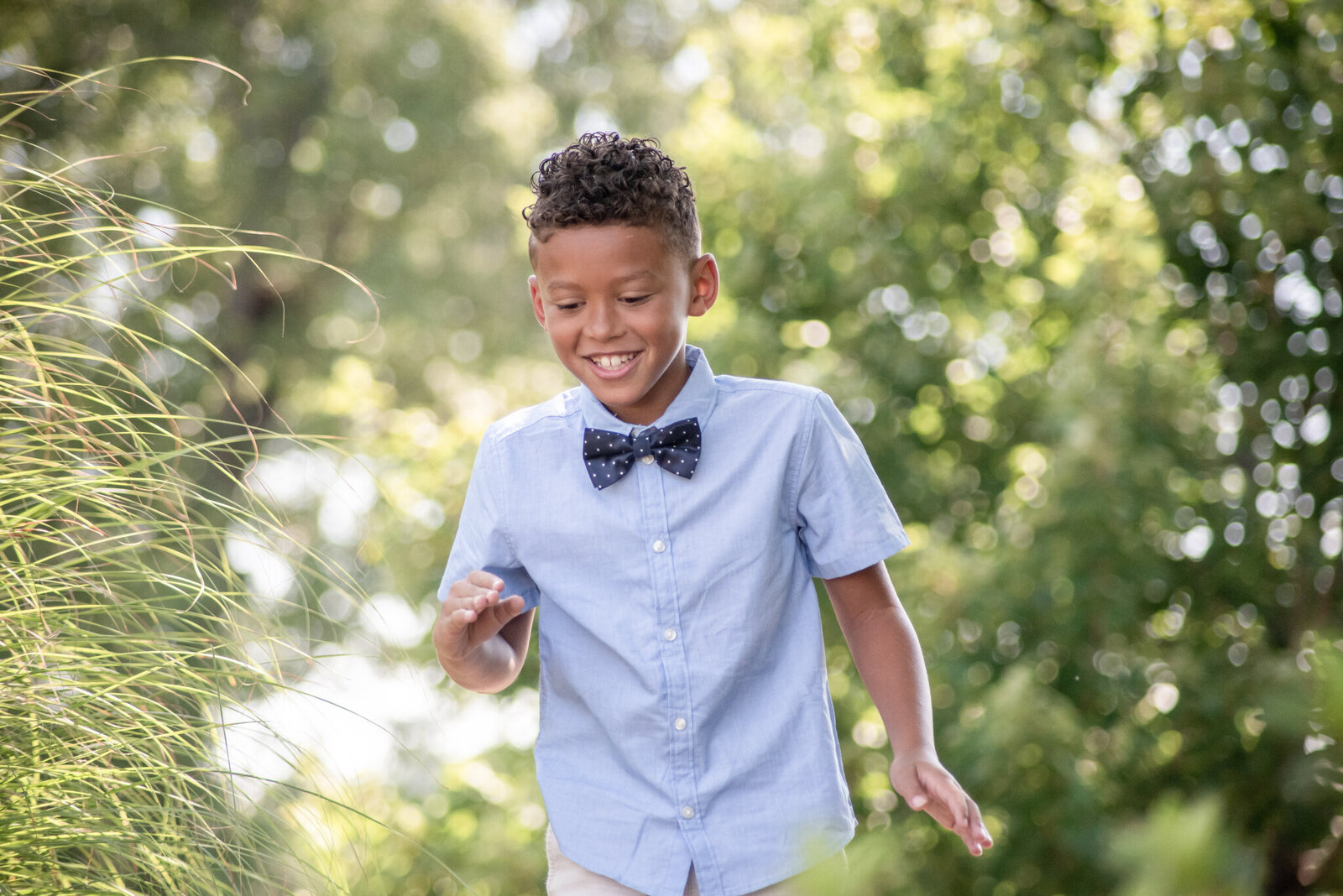 young by in a blue dress shirt and blue bow tie laughing at the camera photographed by Millz Photography in Greenville, SC