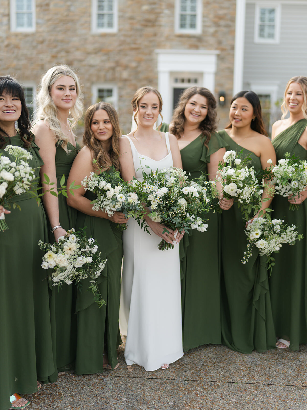 Bridal party with forest green dresses and garden inspired bouquets of white and green