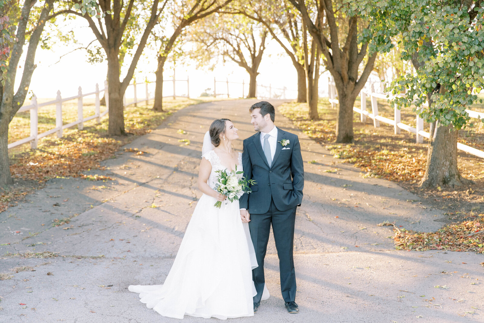 Bride and groom pose at Executive Hills Polo Club driveway at sunset