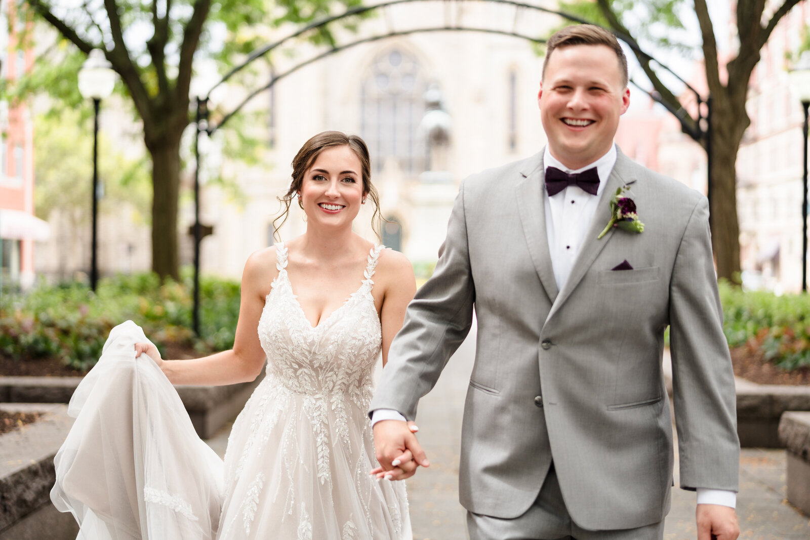 Bride and groom hold hands and run towards the camera in Piatt Park in Cincinnati