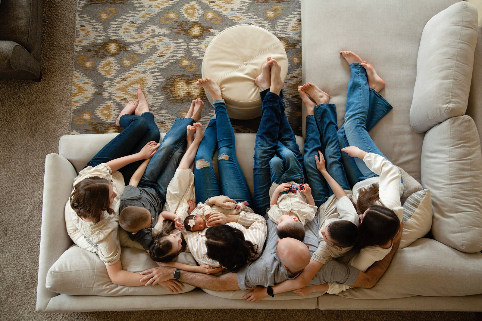 Family of 9 sitting on the couch snuggling - shot from above.