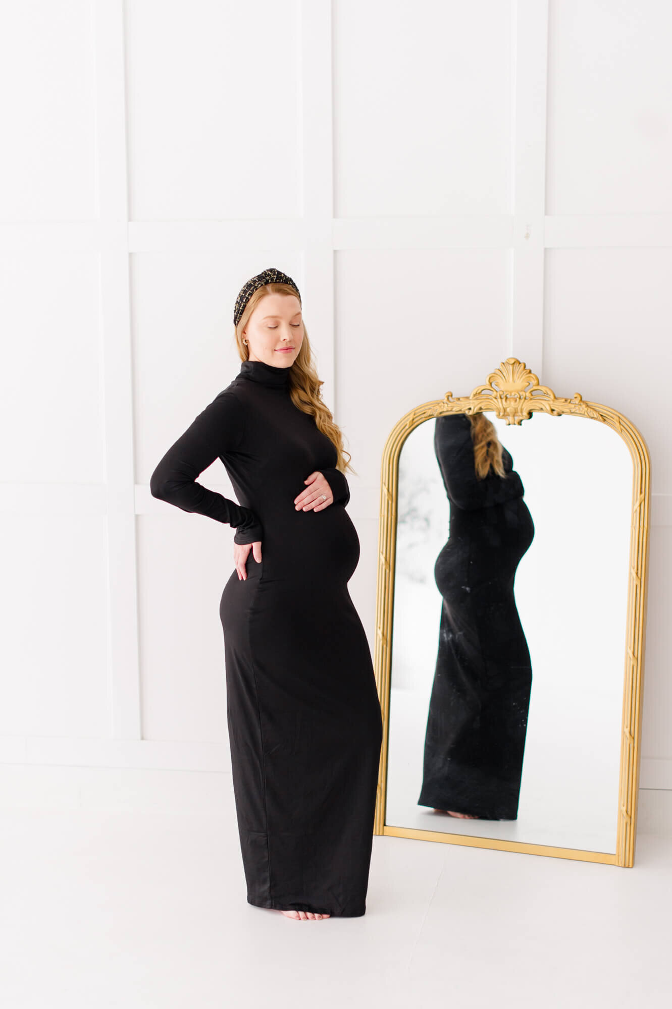 Beautiful elegant maternity photos of mom standing next to a mirror holding her belly