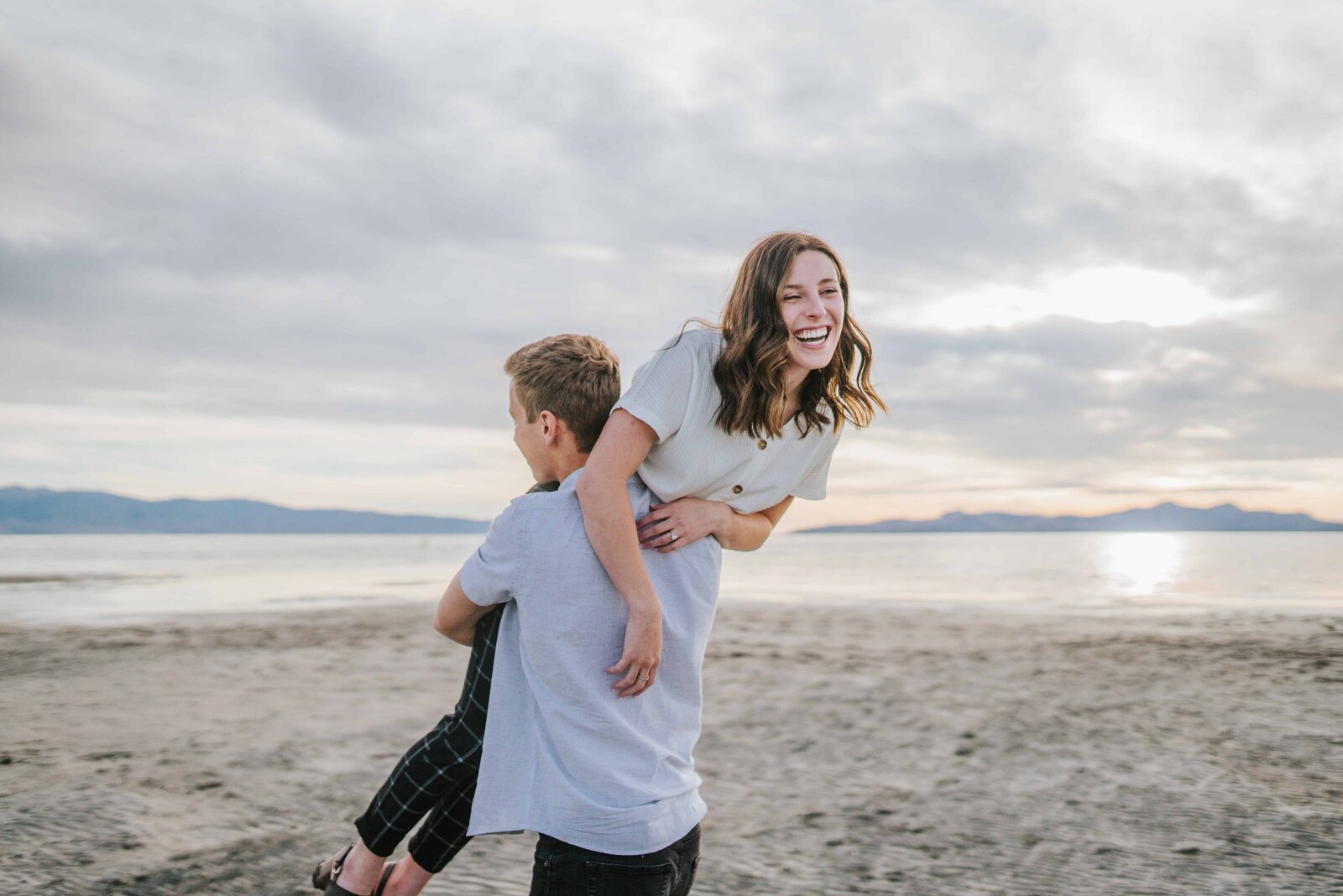Sacramento Wedding Photographer captures man lifting woman up during outdoor engagements on beach