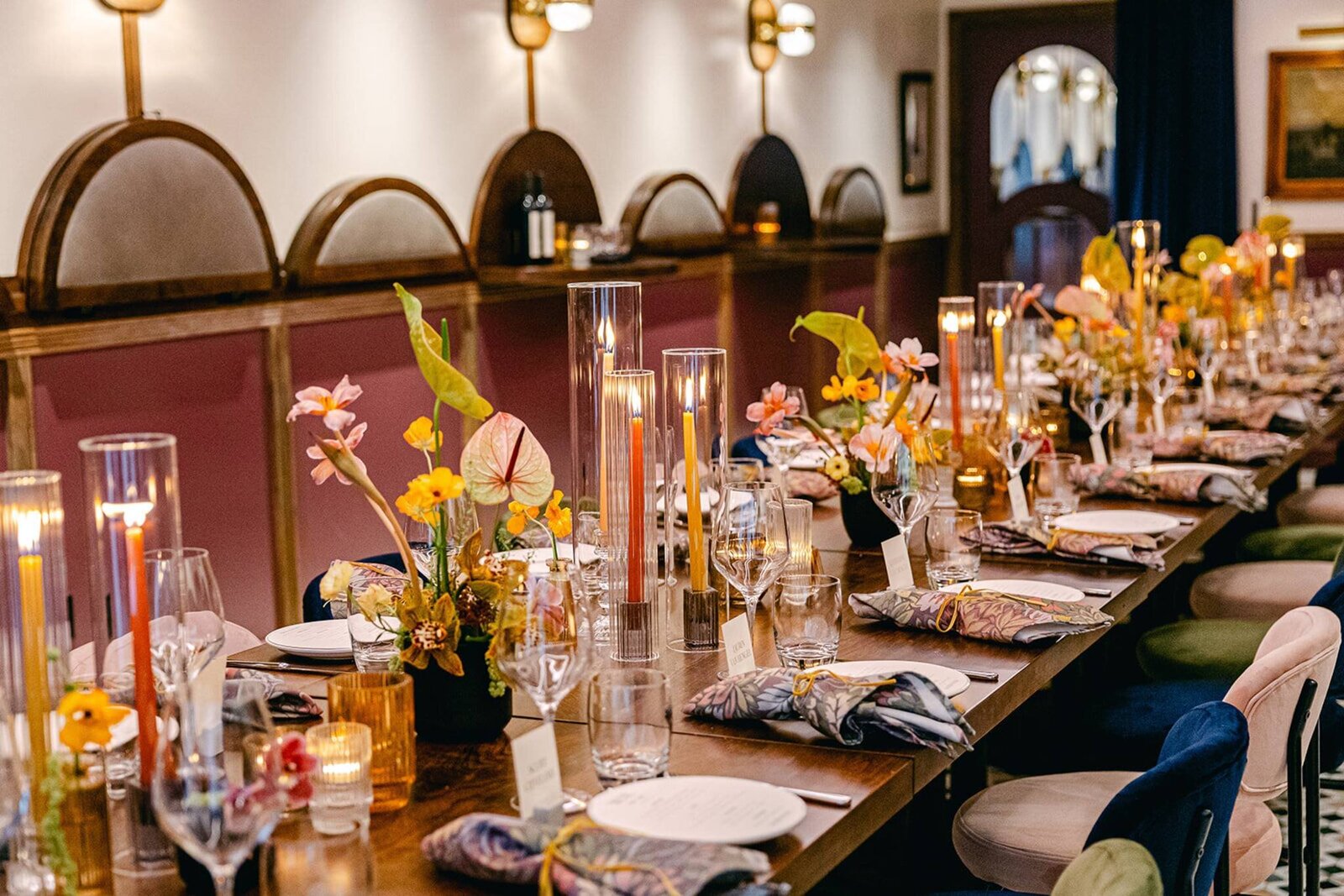 Chic wedding reception setup with a long dining table, lush floral centerpieces, candlelit ambiance, and sophisticated decor.