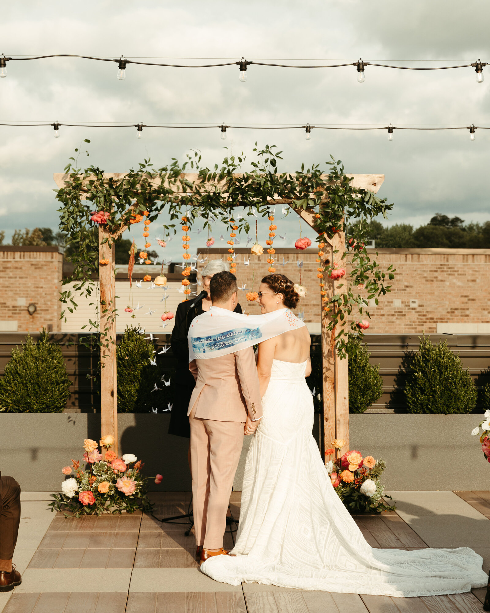 Brides standing at alter of flowers on a rooftop