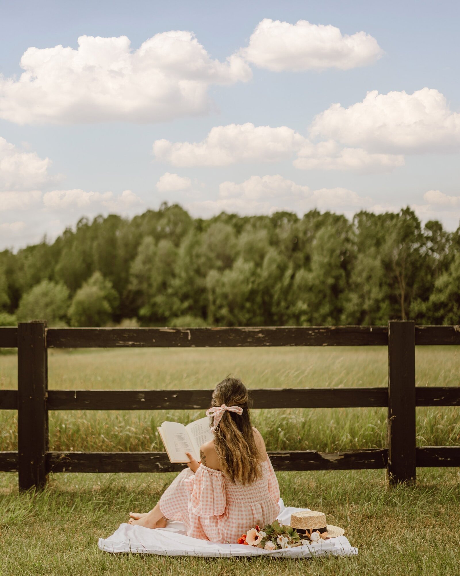 a-woman-reading-a-book-while-sitting-on-a-picnic-blanket