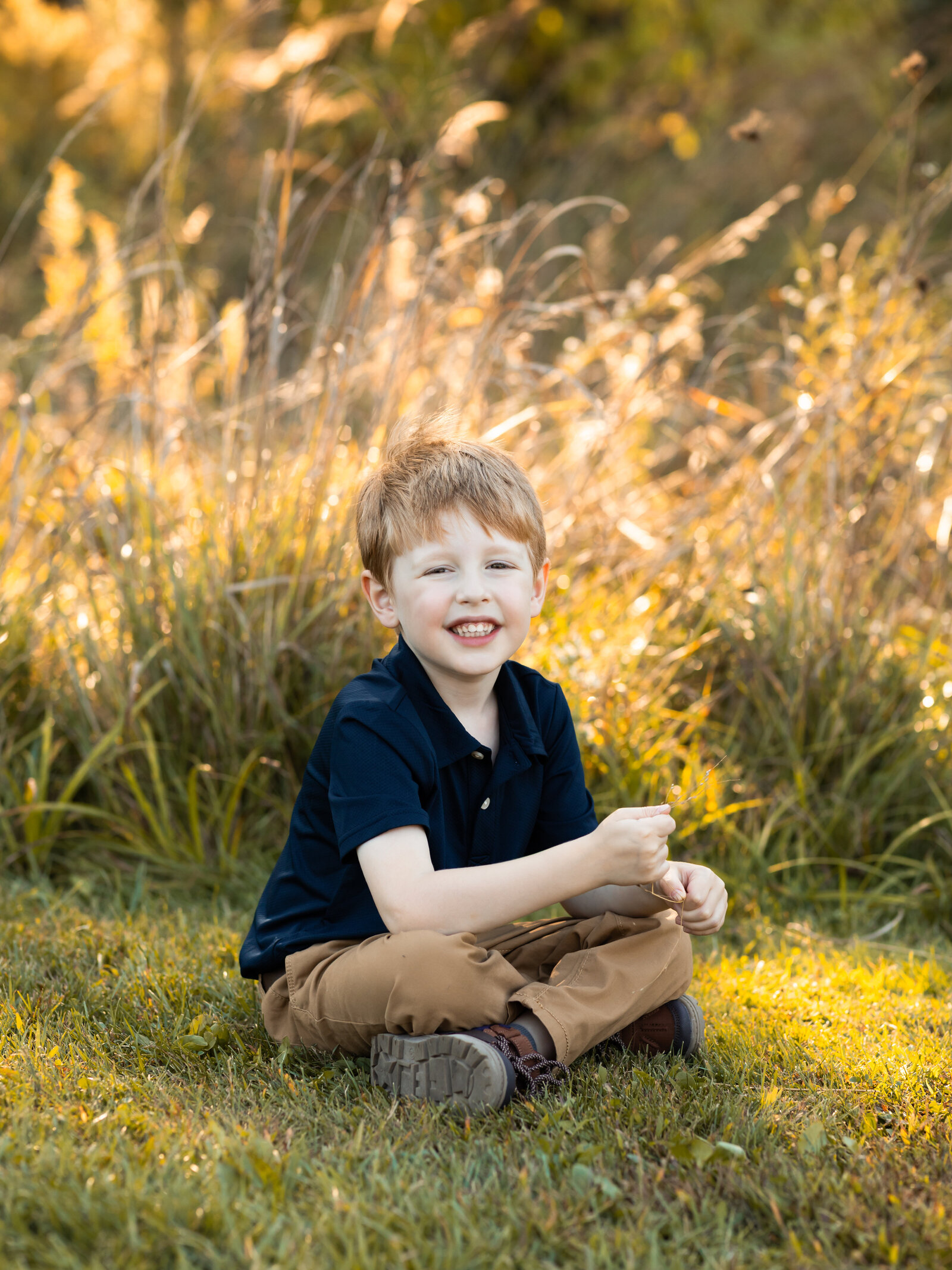little boy sitting in grass posing for family photos
