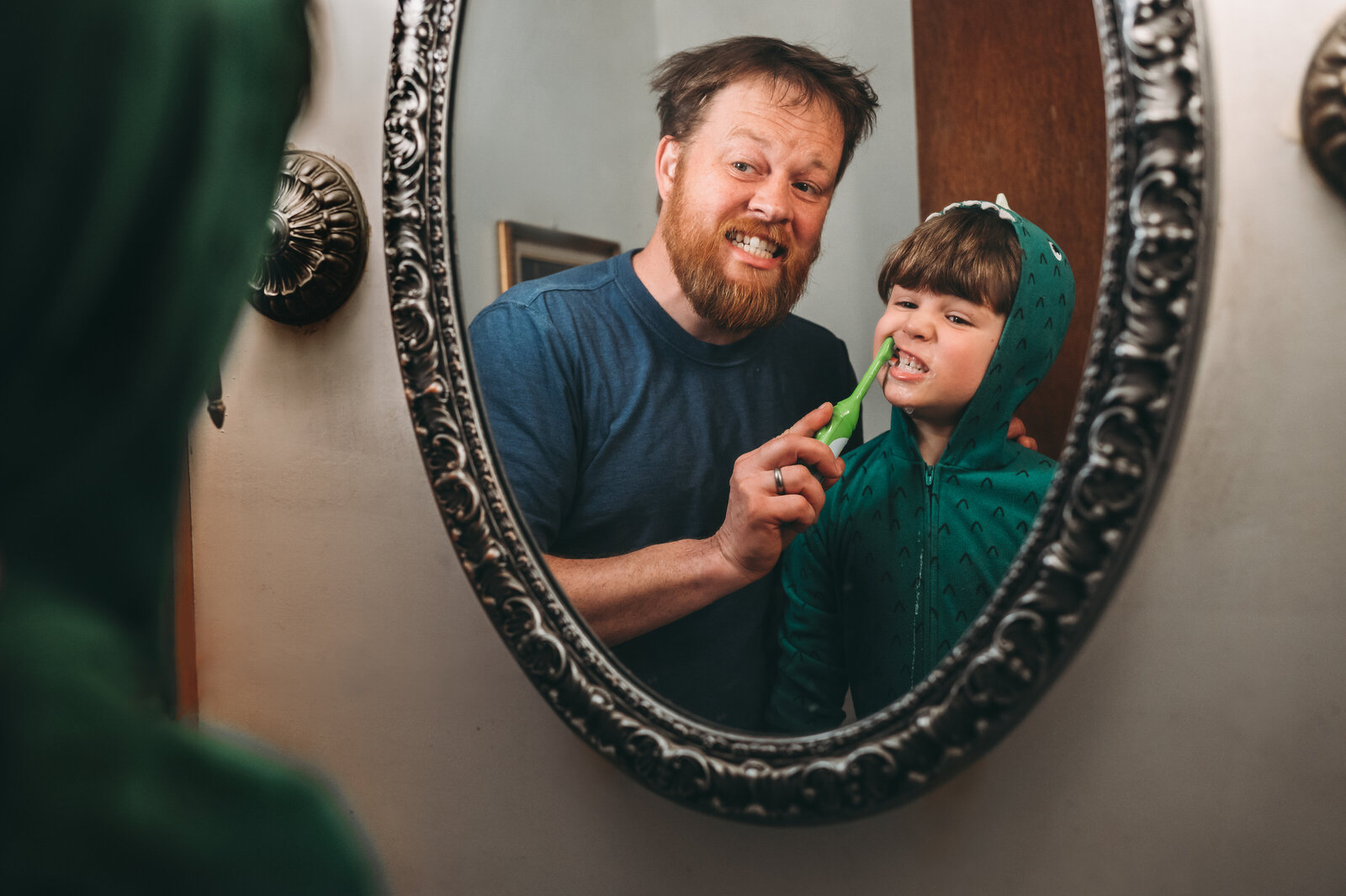 Dad helping son brush teeth