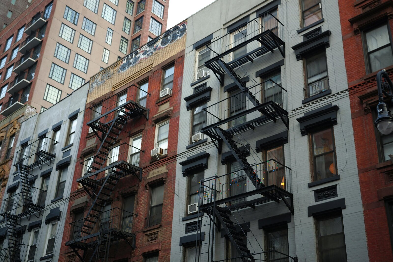 NYC apartment buildings with fire escapes and varying architectural styles.