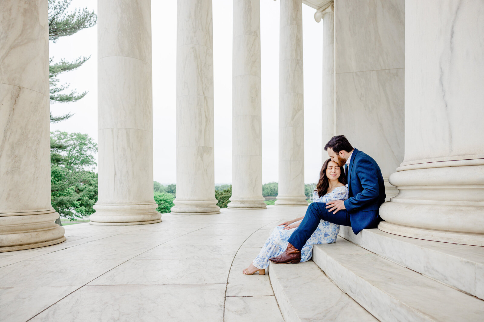 couple sitting and kissing engagement blue and white dress jefferson memorial columns