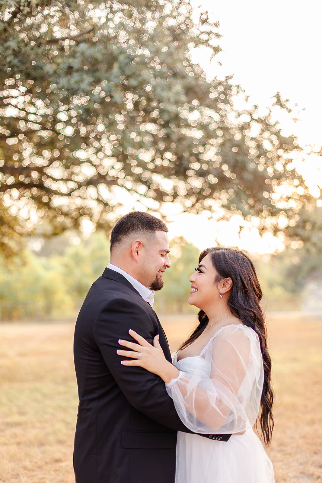 old town spring maternity session of husband wearing a dark suit and wife wearing a white dress while facing and smile at each other