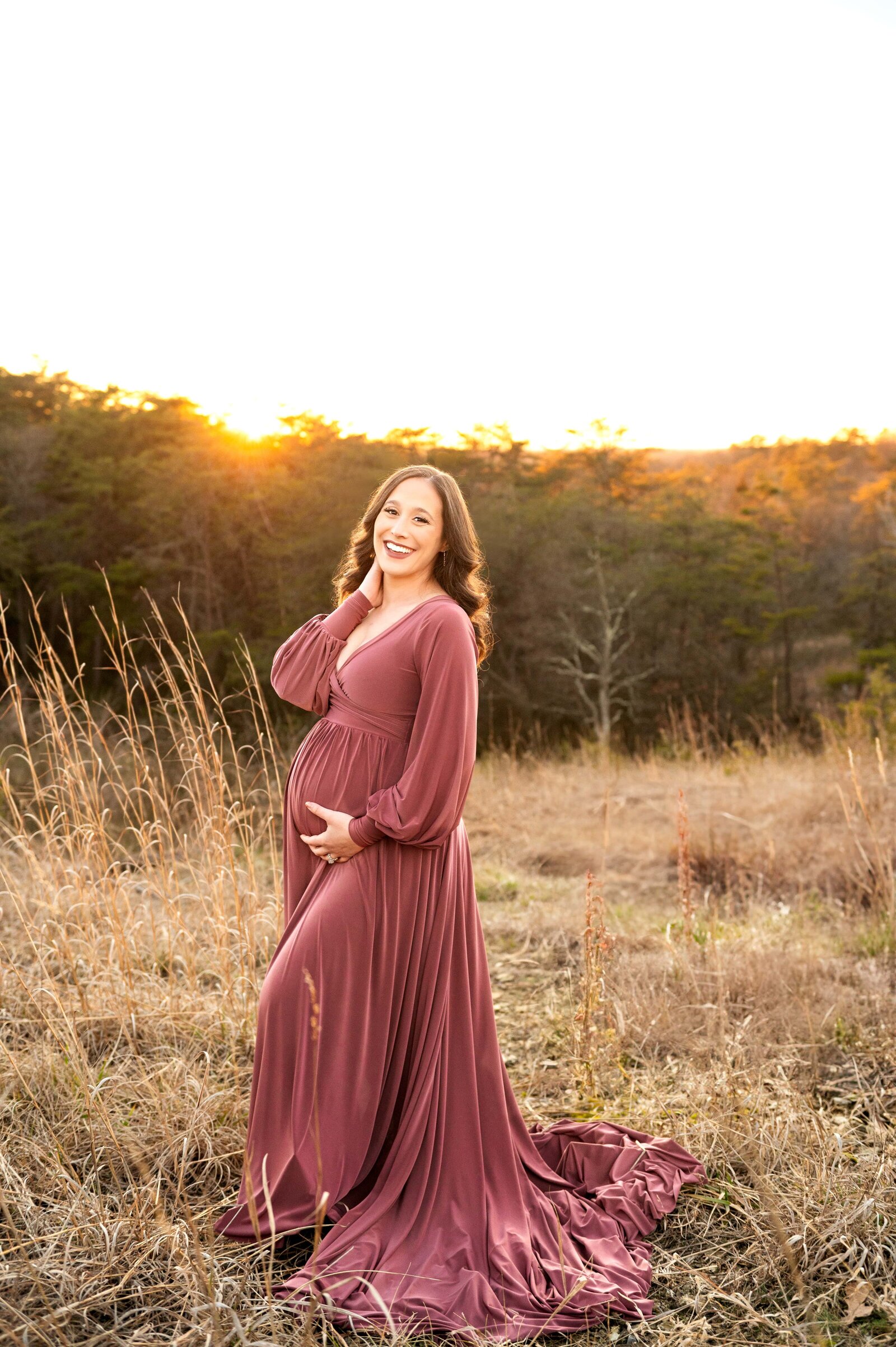 mom holds her pregnant belly while smiling