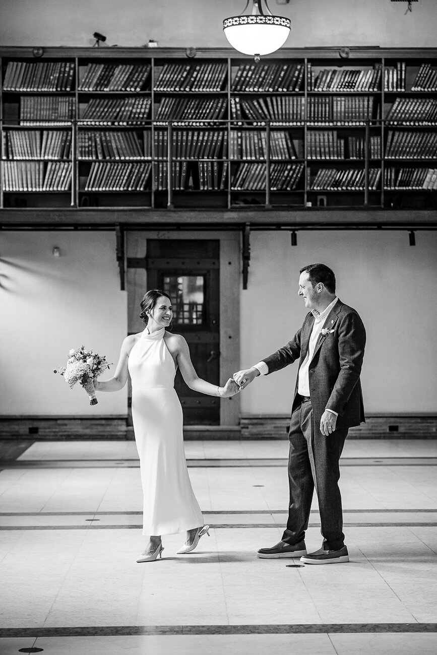 black and white portrait of bride and groom dancing in boston public library