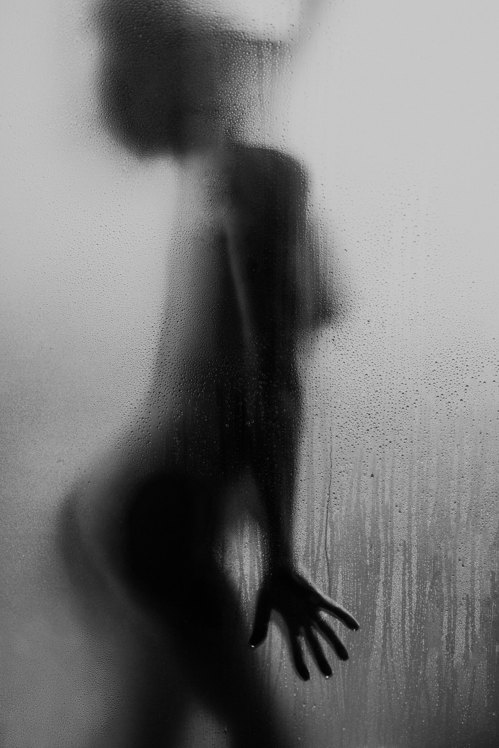 A woman's silhouette standing behind a steamy shower door