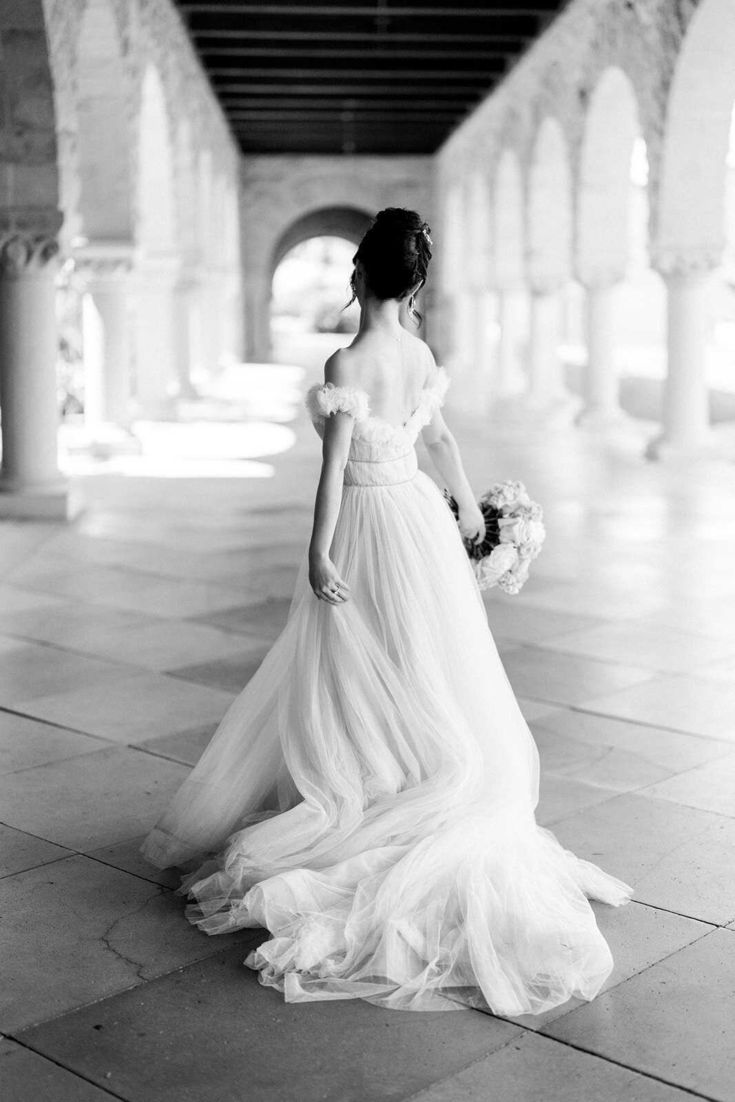 The bride gracefully walks through Stanford University, capturing a beautiful moment from her wedding day in California.