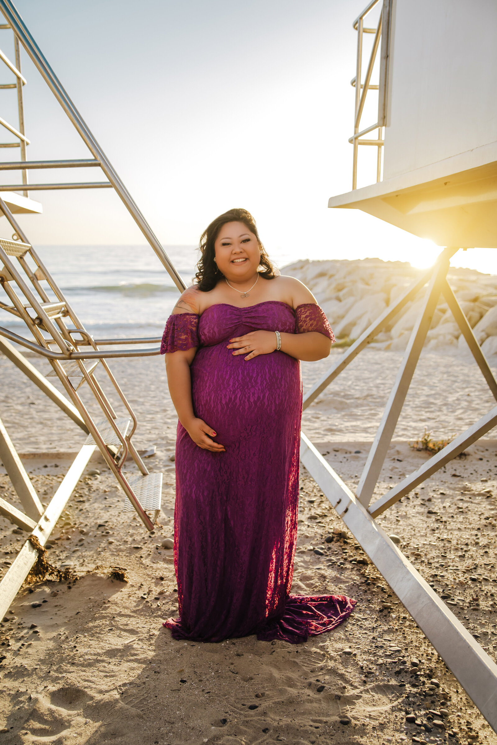 Maternity Photographer, an expectant mother stands nears a life guard  tower