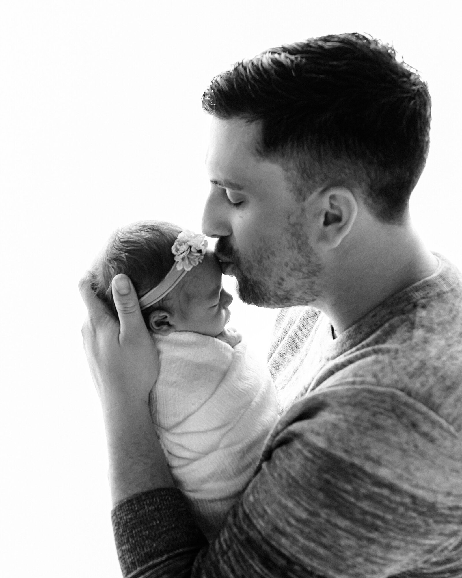 dad kissing newborn baby girl for studio portrait