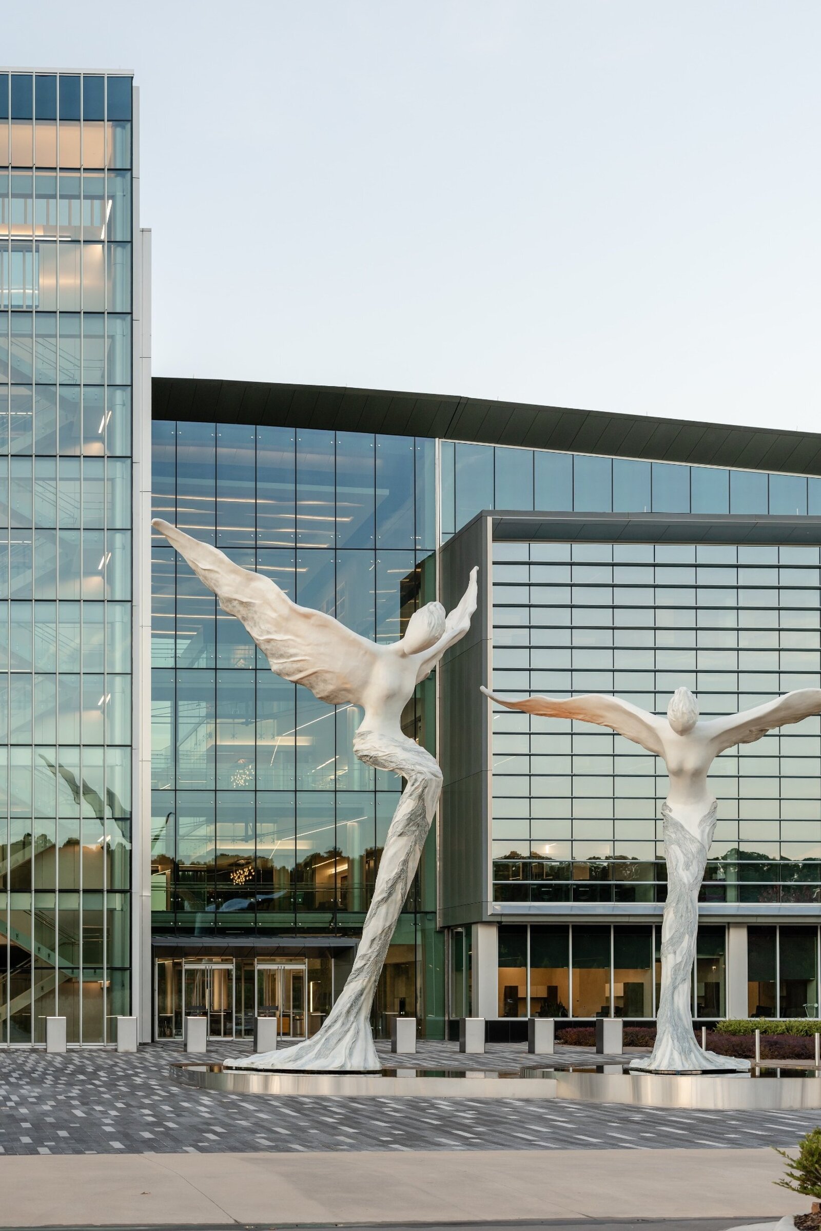 Modern commercial building with dramatic glass architecture and large winged sculptures, part of a landscape installation project by Better Lawns and Gardens in Little Rock, Arkansas.