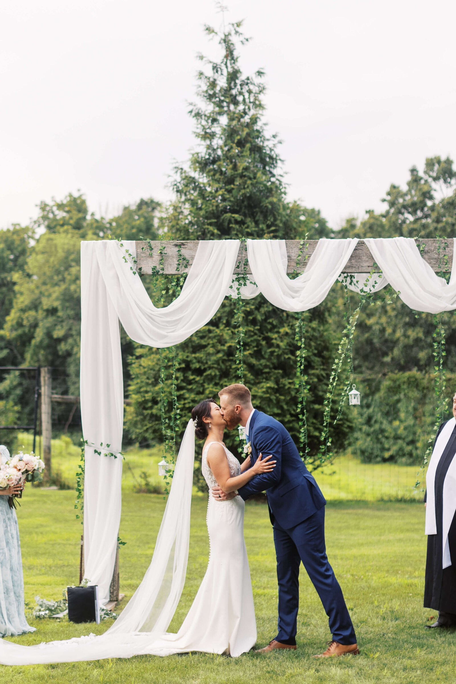 Bride and groom share their first kiss as husband and wife during outdoor wedding ceremony.