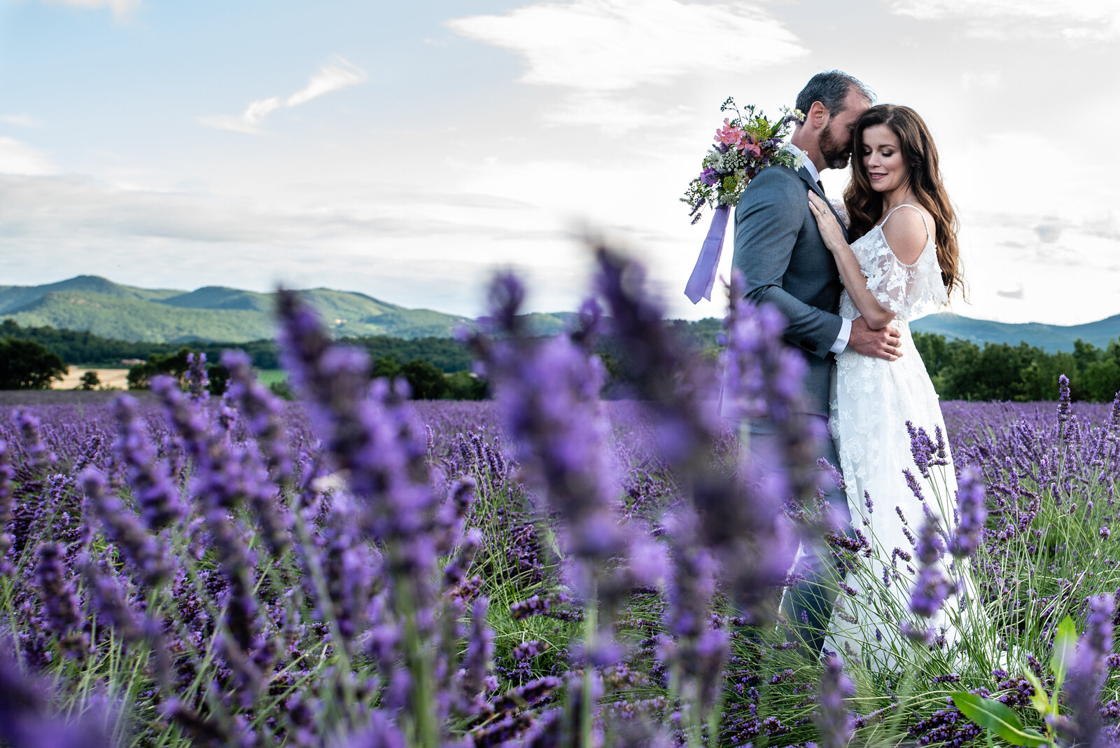 wedding photography lavender field bride and groom snuggling standing lavender in the foreground by Allison Burton