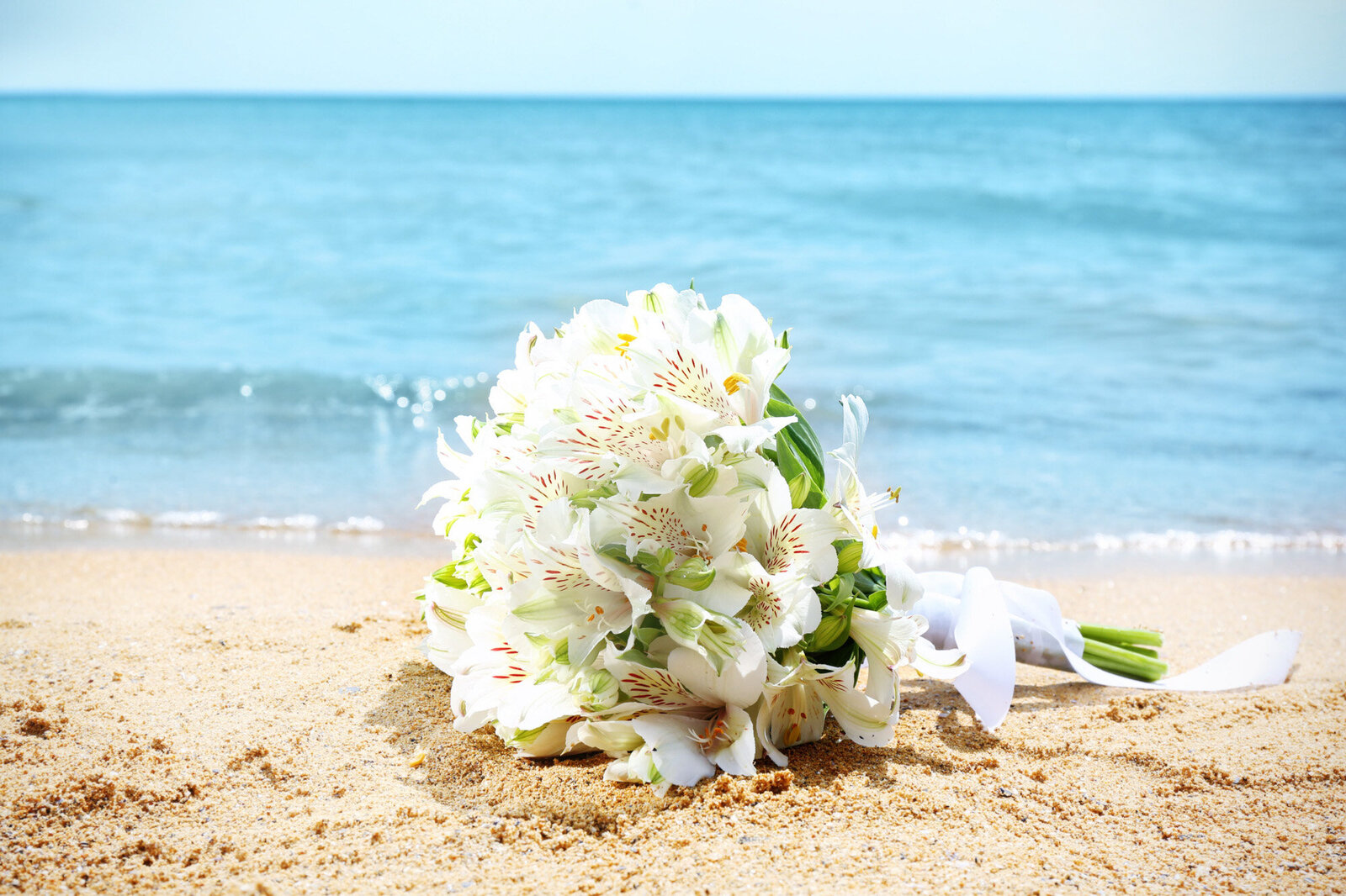 White floral bouquets on the sand on the seashore