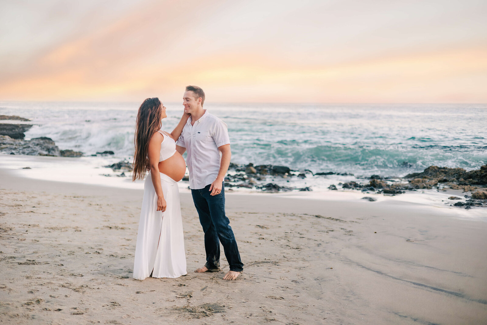 Couple looking into each others eyes during maternity session in Laguna Beach, CA by Ashley Nicole Photography.