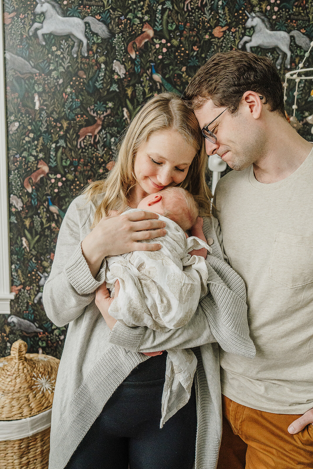 parents snuggle newborn baby to chest in nursery