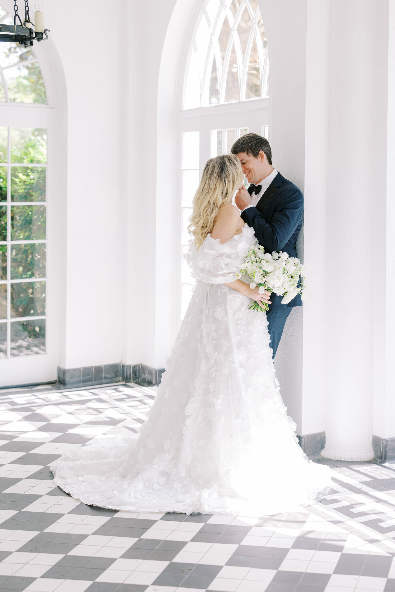 A bride and groom steal a kiss on the checkerboard floor of Lowndes Grove, at their waterfront wedding in Charleston, SC