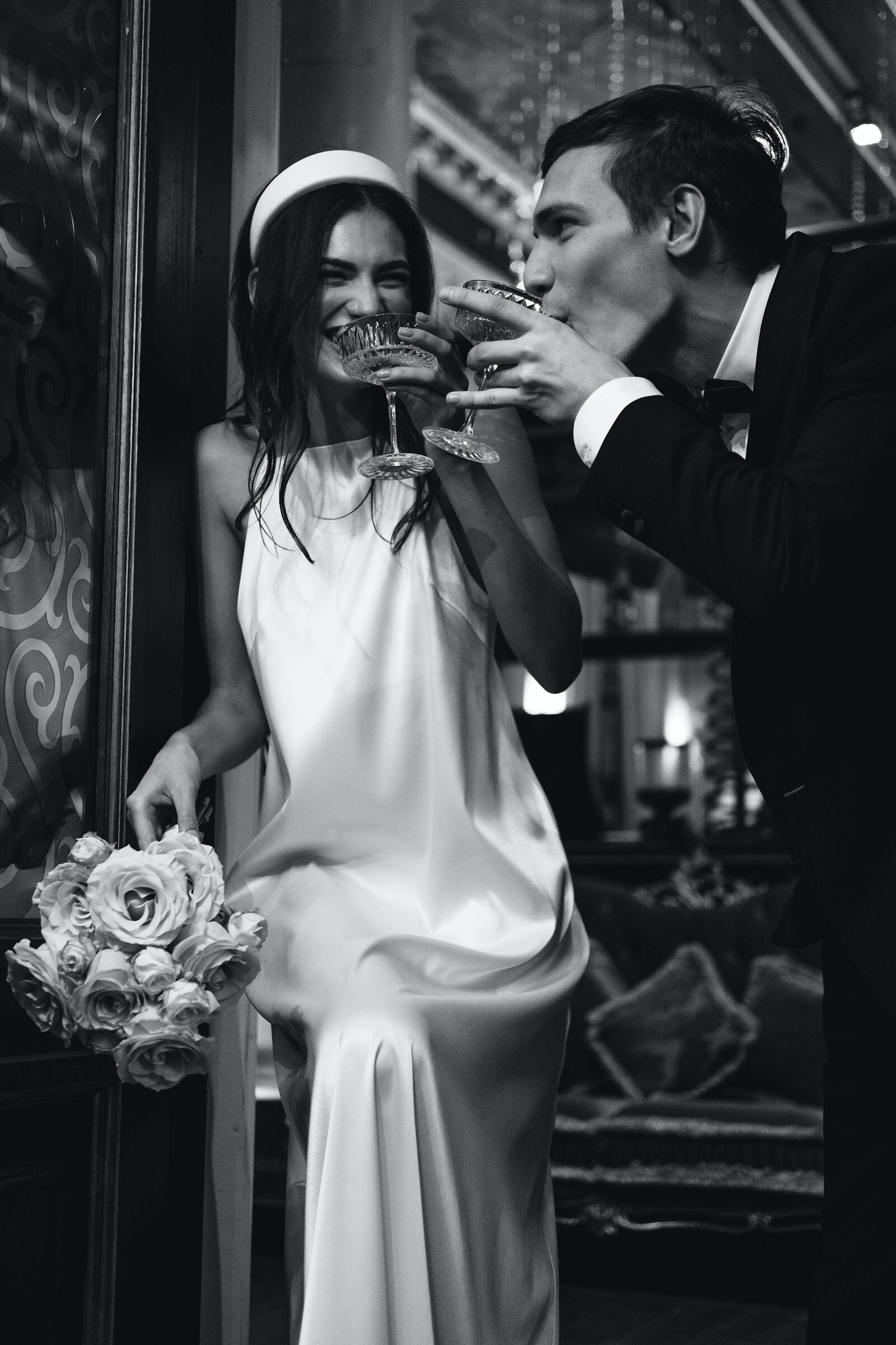 black and white image bride and groom laughing drinking champagne