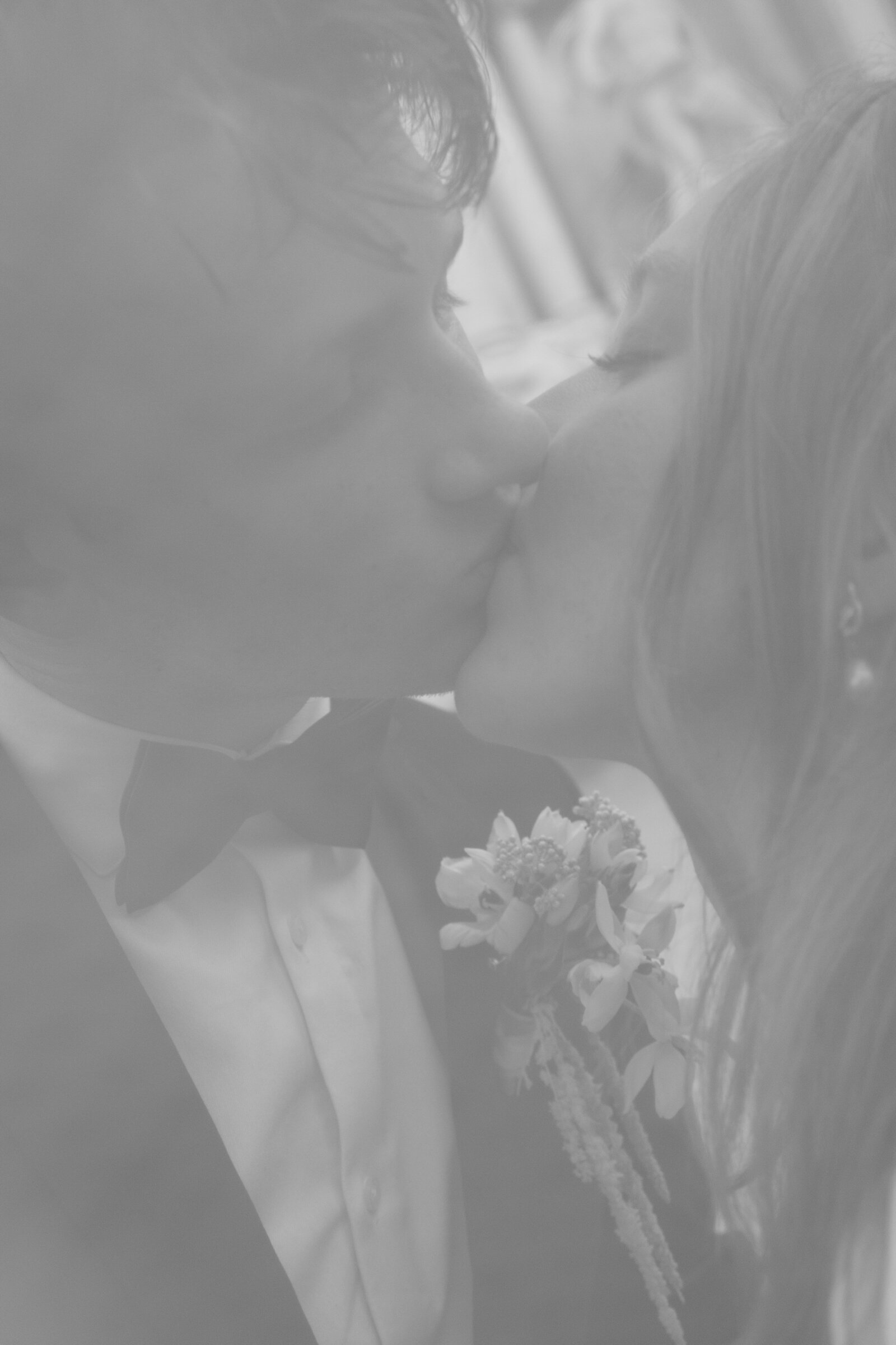 Groom holding brides dress in a black and white photo