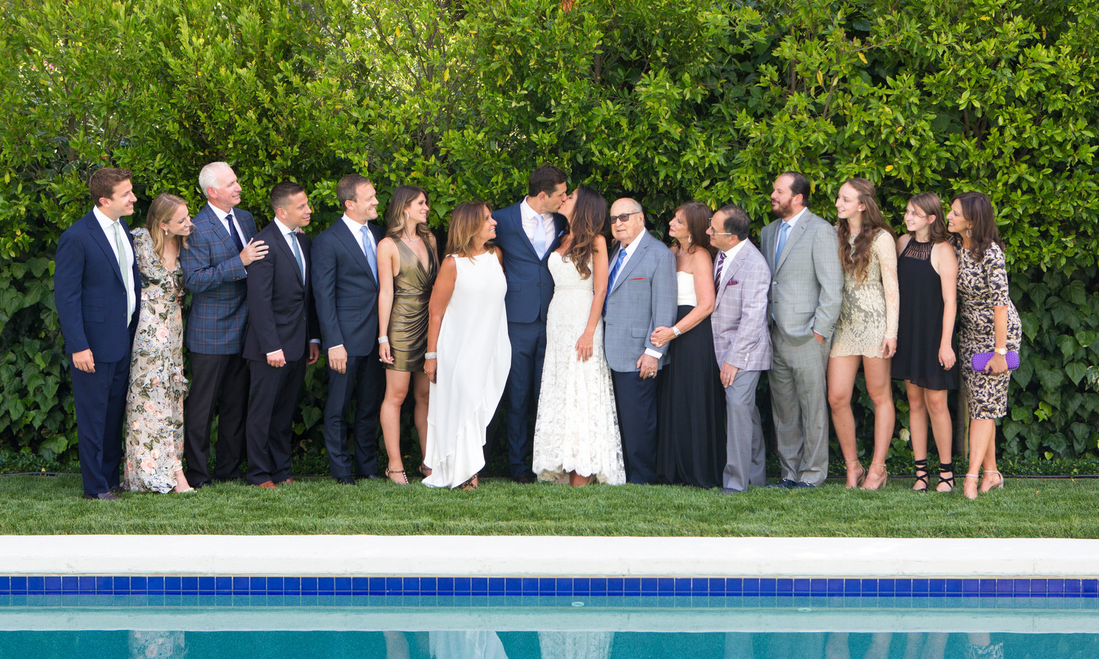Overlooking a gorgeous pool, the bride and groom pose with their family members