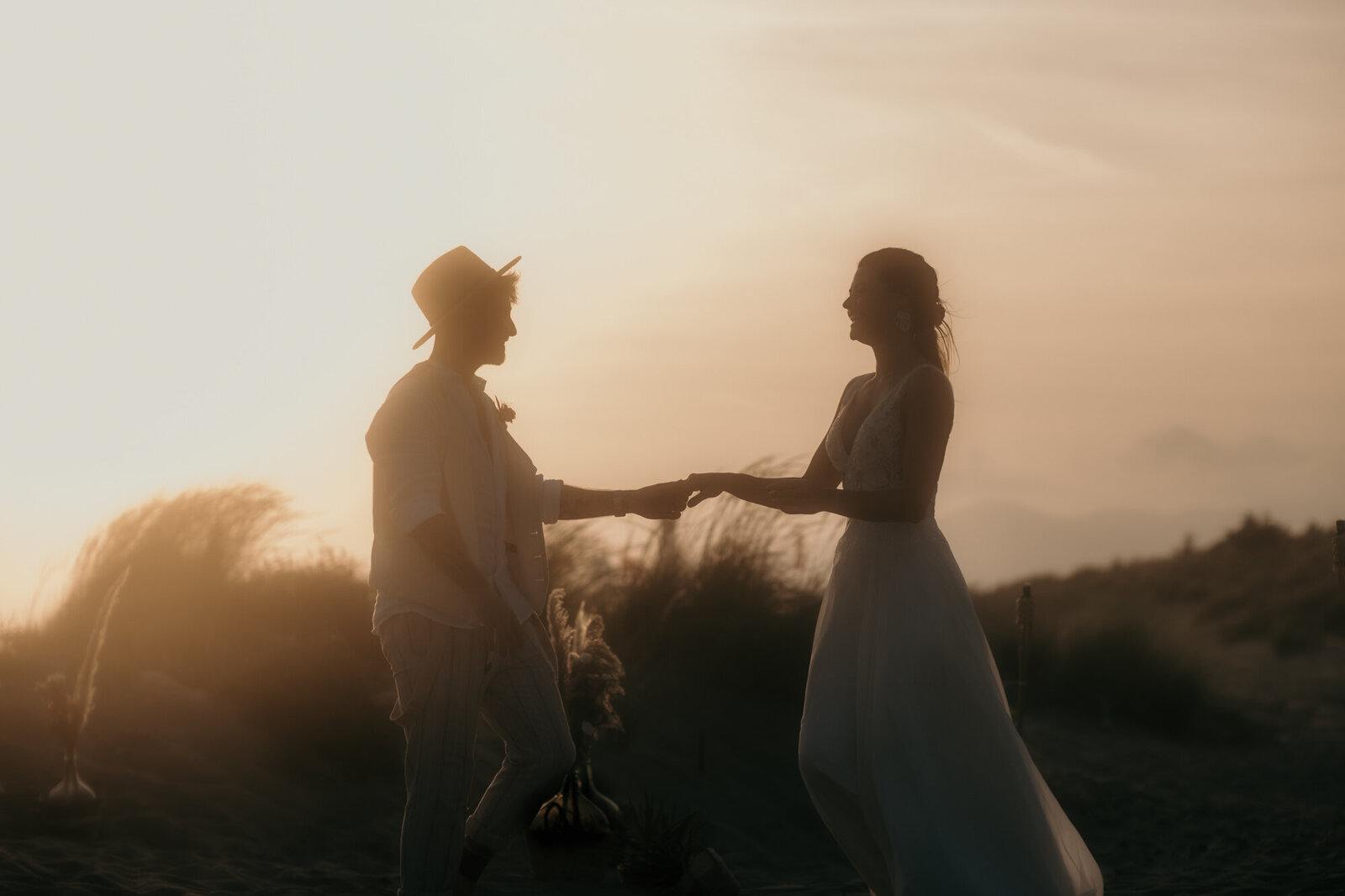 Wedding couple smiling at each other during golden hour at the beach.