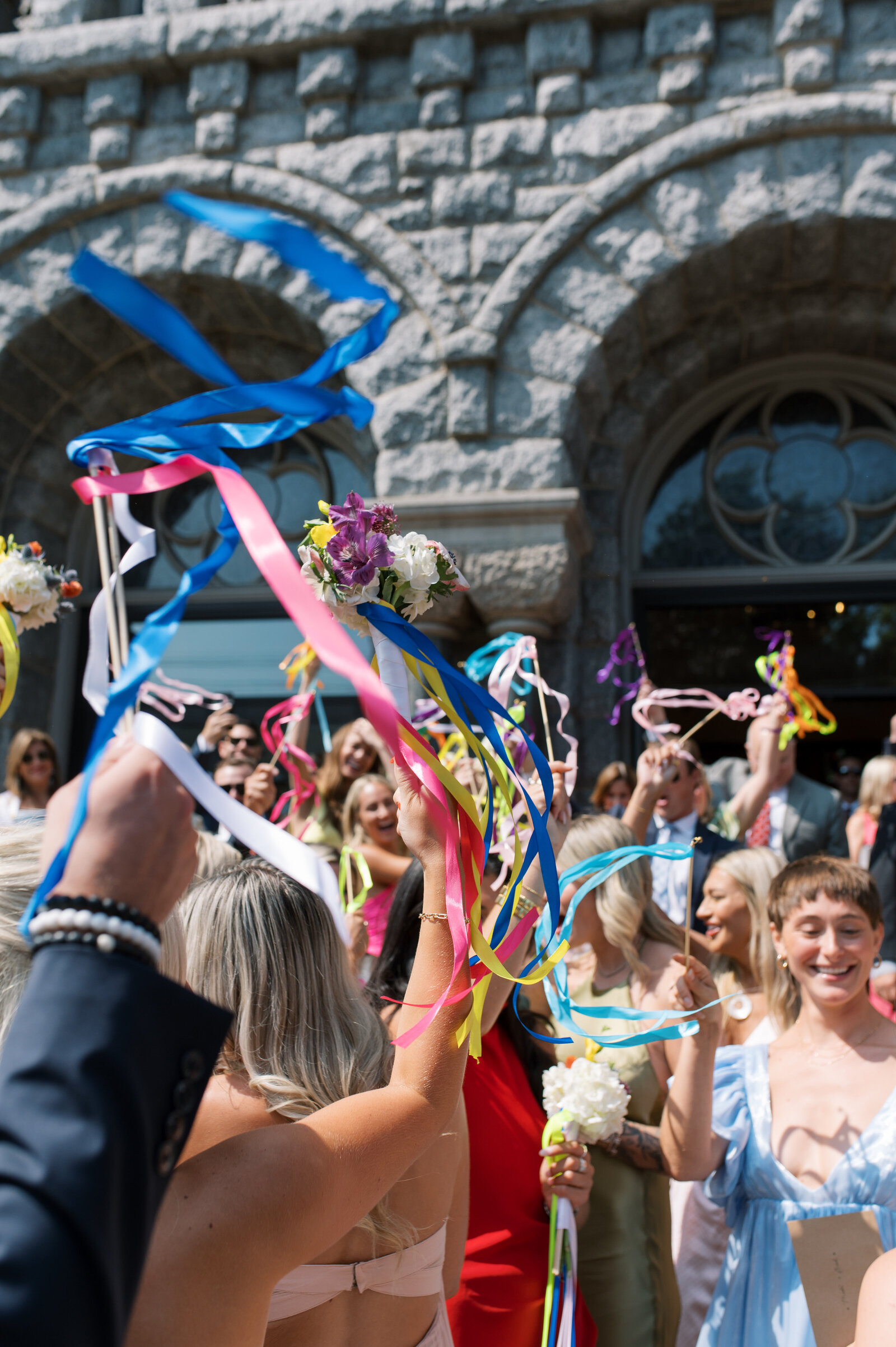 guest waving colorful ribbon wands at wedding ceremony