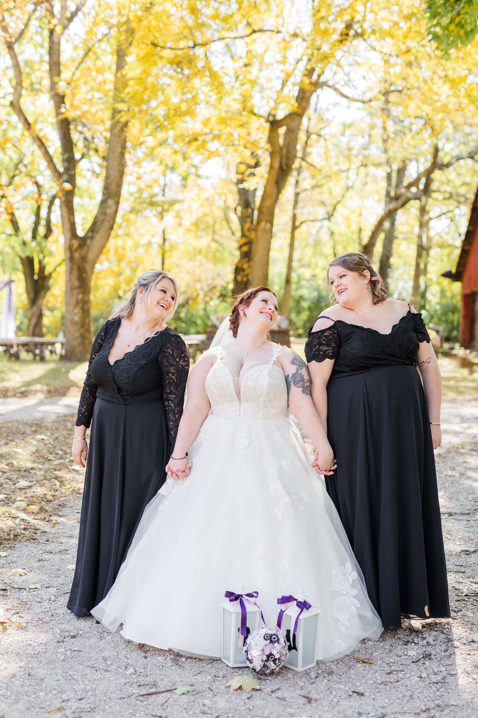 bride holding hands with her two bridesmaids who are wearing black at the ohio barn