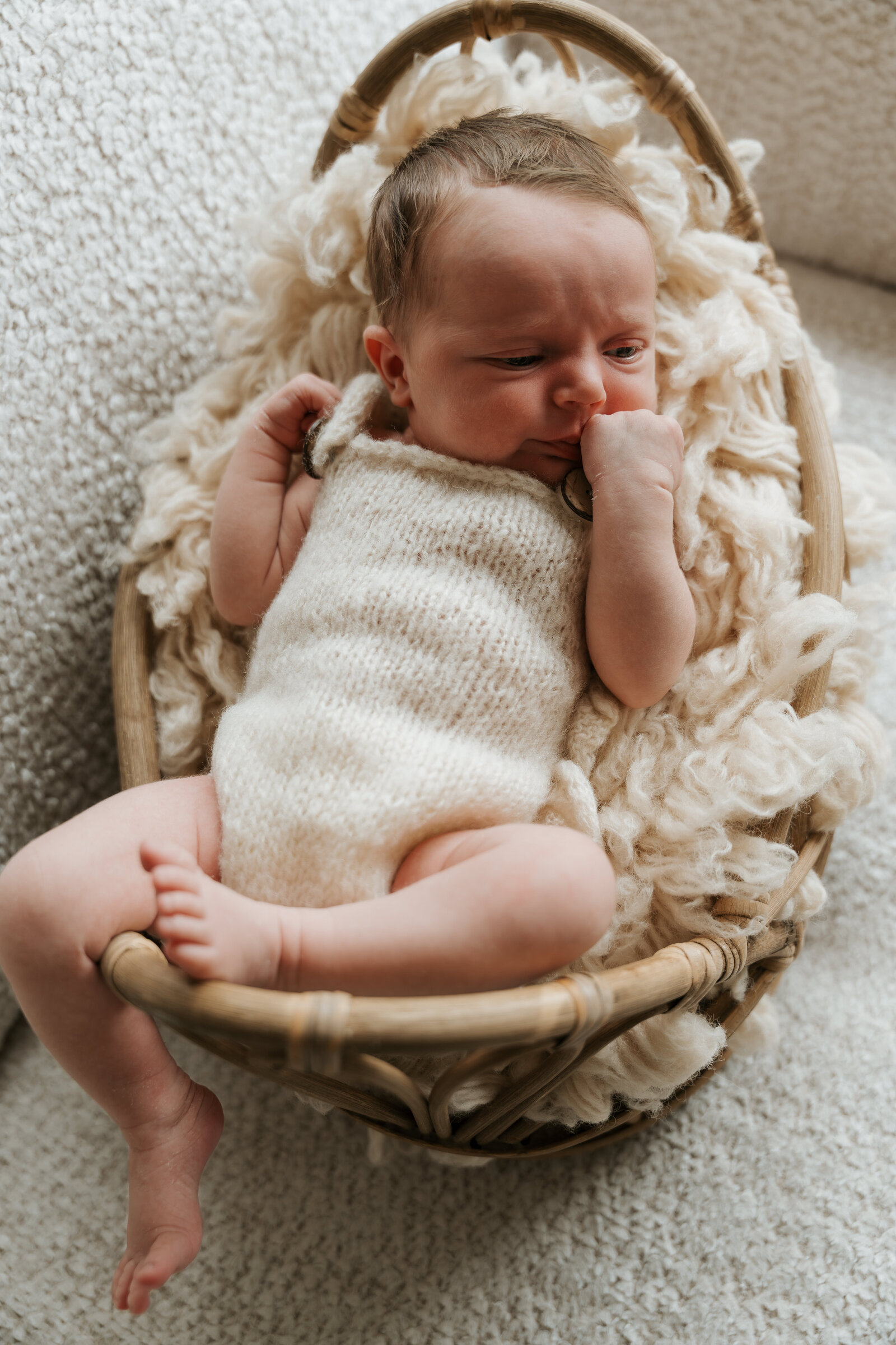 Portret van een pasgeboren baby liggend in een gevlochten mand met wol