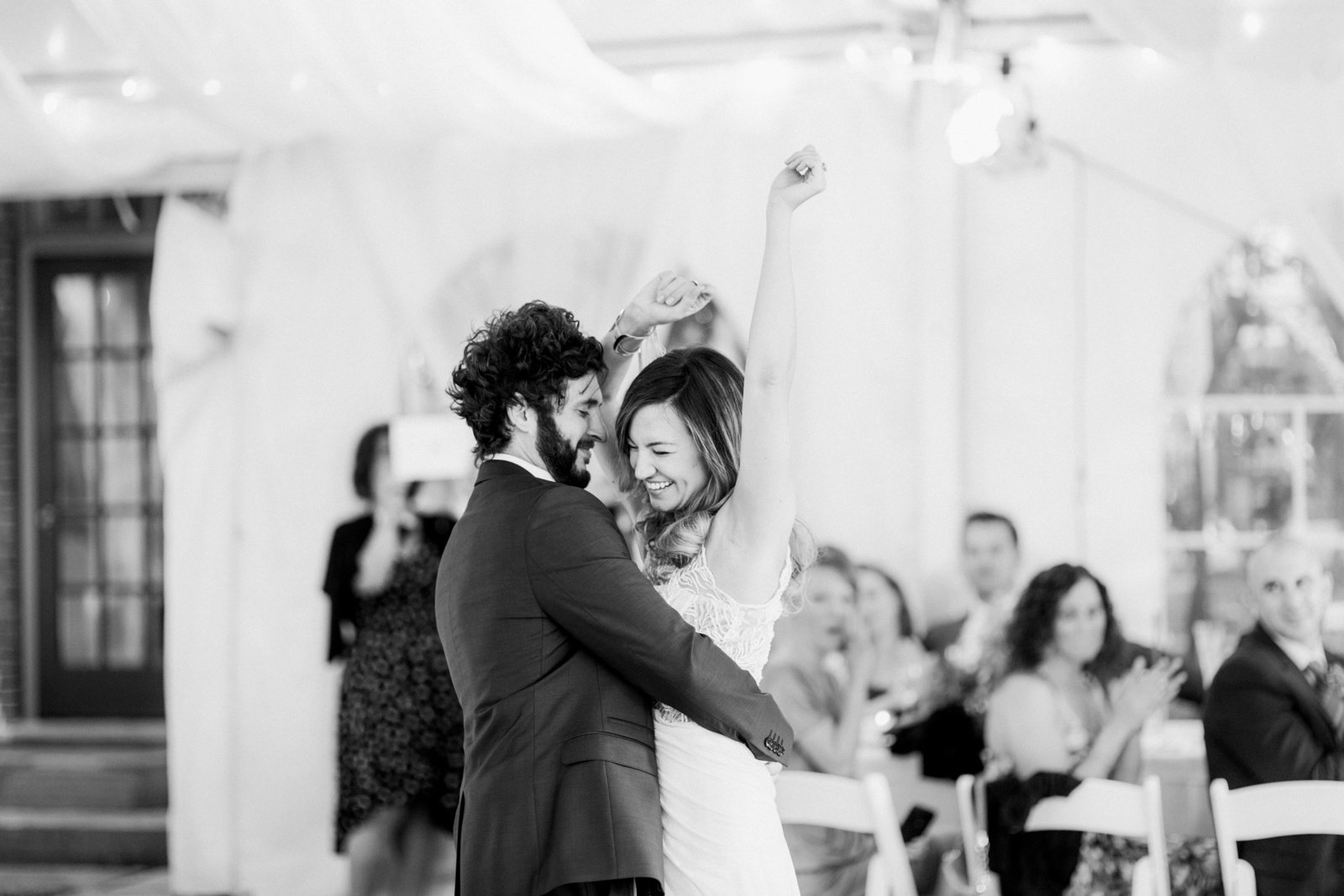 bride throws her arms up in the air during her first dance with her husband