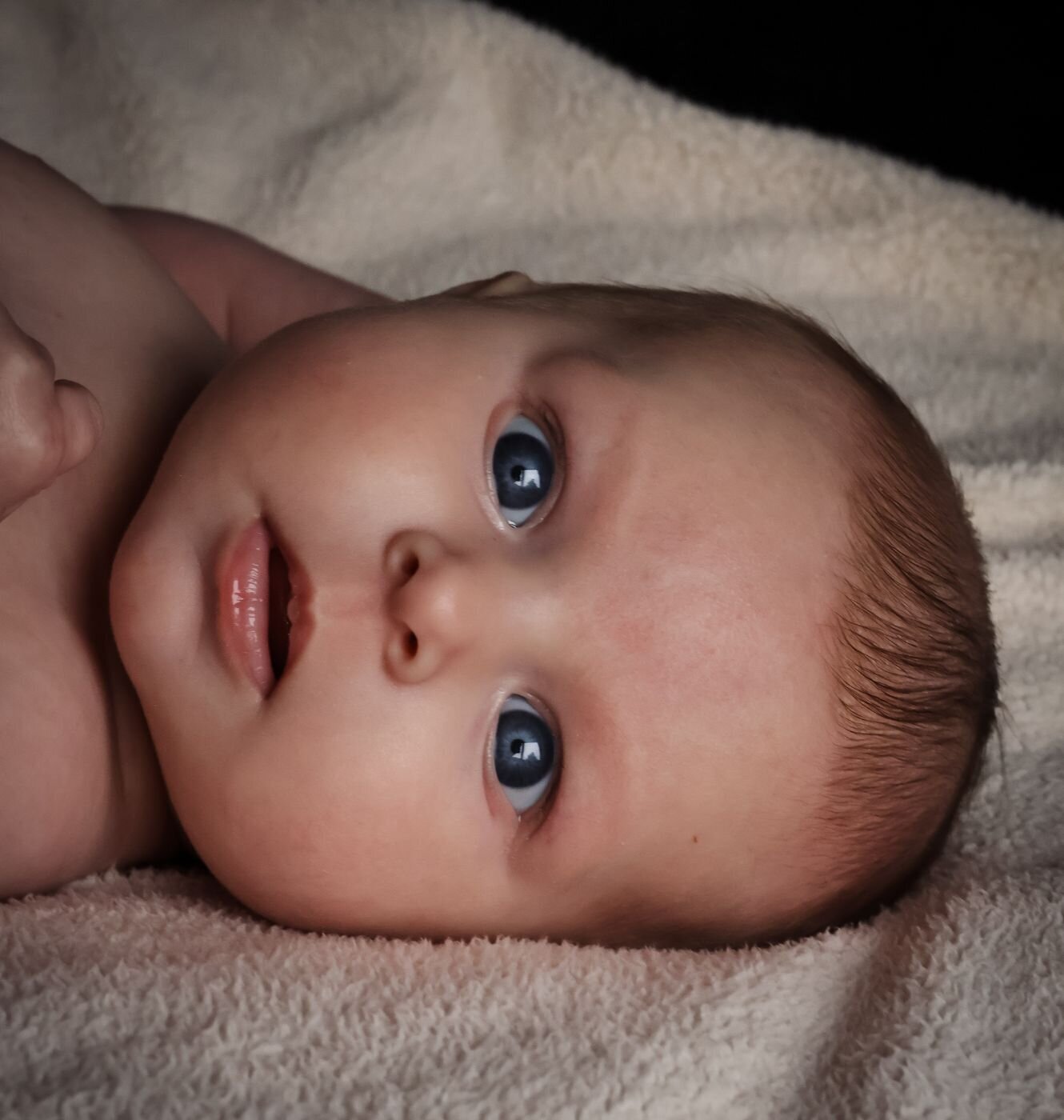 Detailfoto van het gezichtje van een pasgeboren baby, met de focus op de ogen en de zachte huid