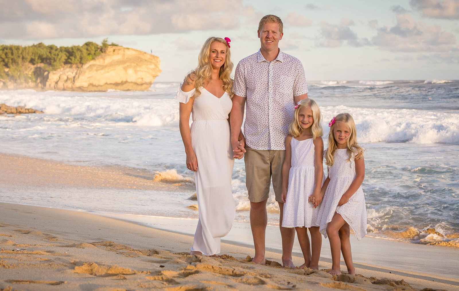 Family portrait all wearing white on the sand in Oahu