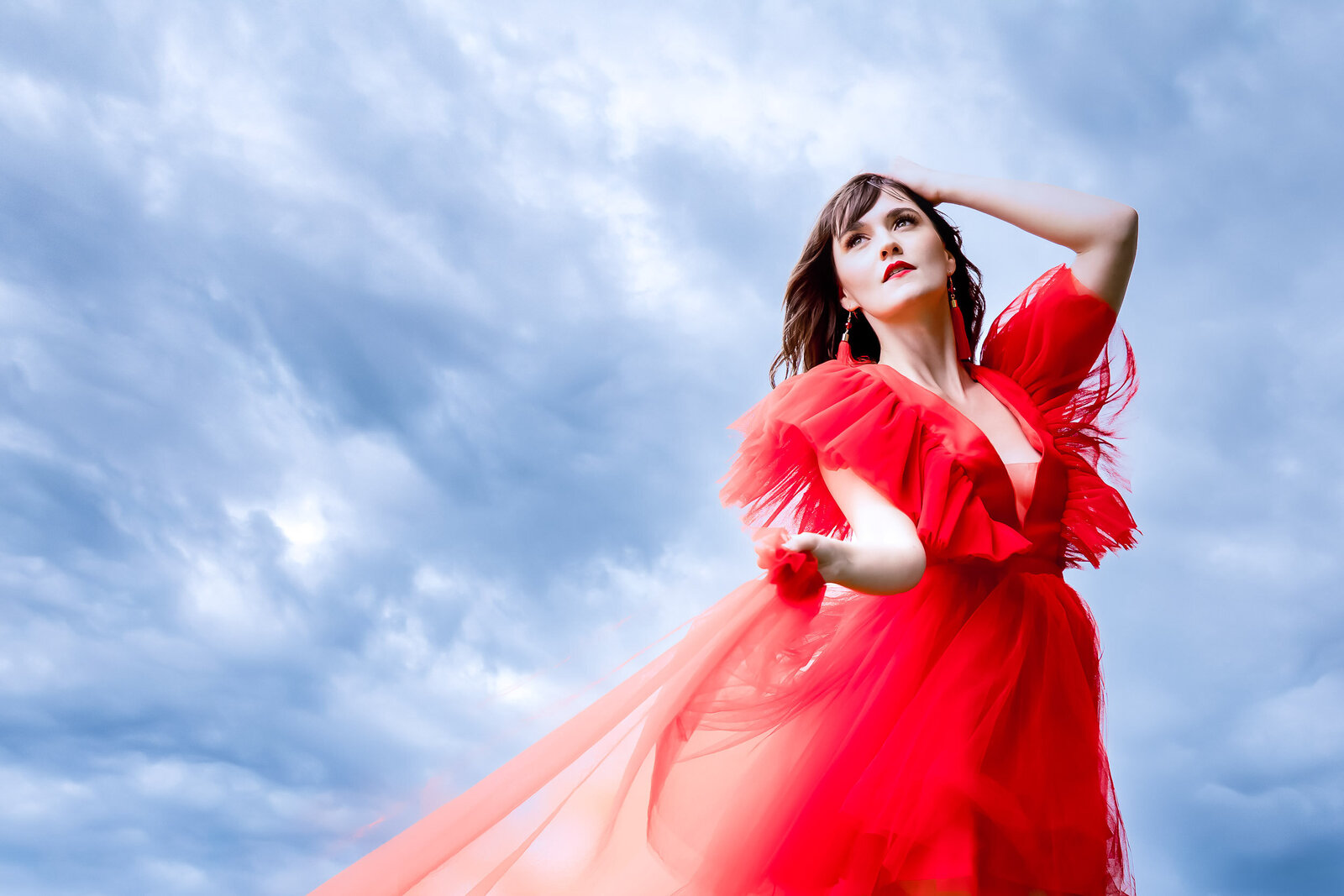 nikki serenity posing in red fly dress with the kansas city sky