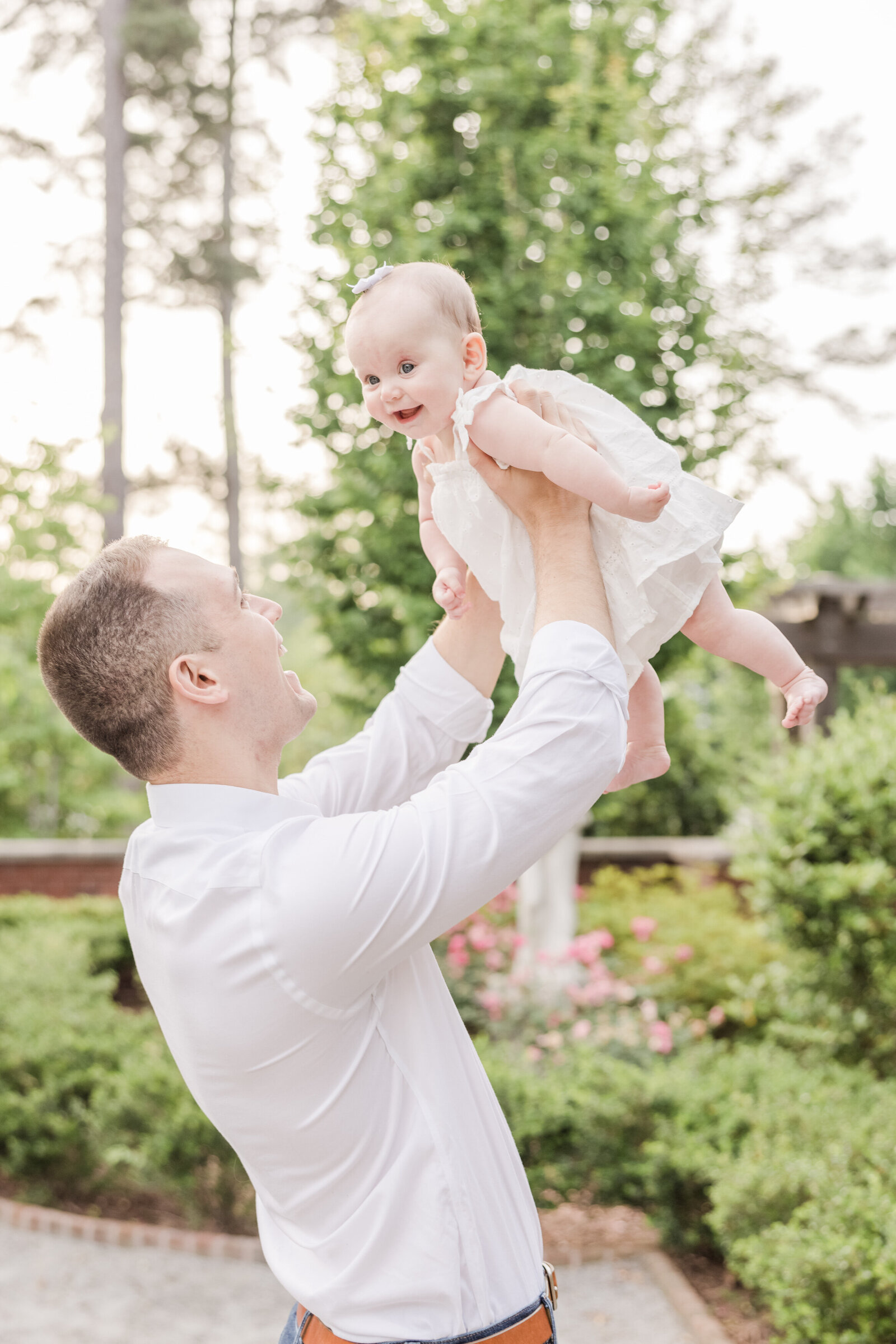 Father holding his smiling daughter up in the air.