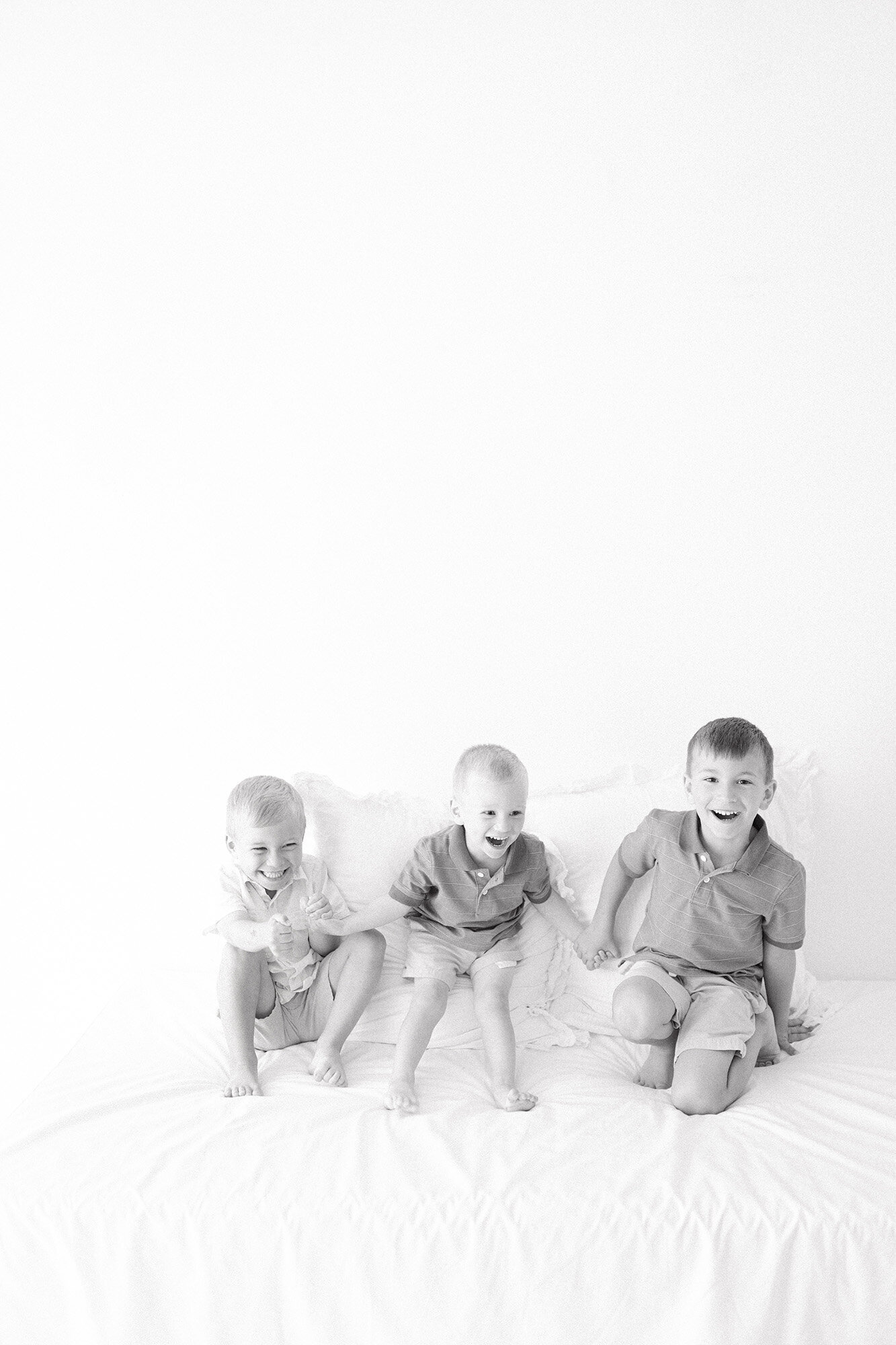 Siblings jumping on a bed during a lifestyle family photography session in Grand Forks, North Dakota