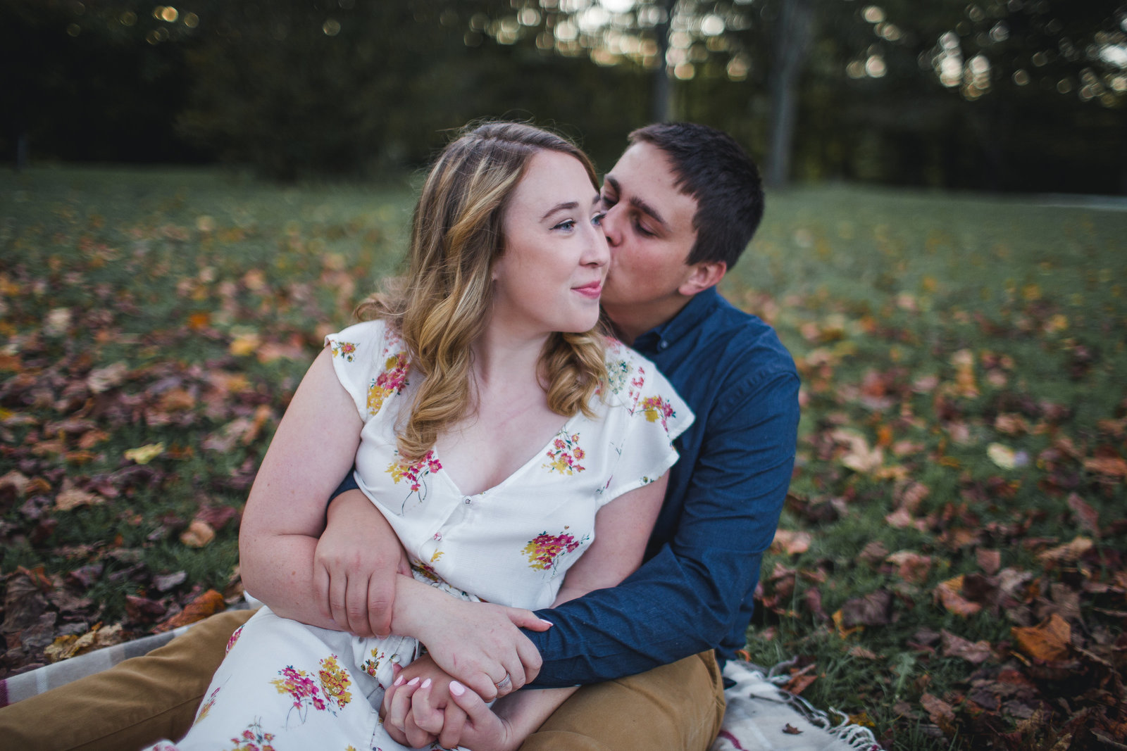 engaged_couple_snuggles_on_ground_in_fall