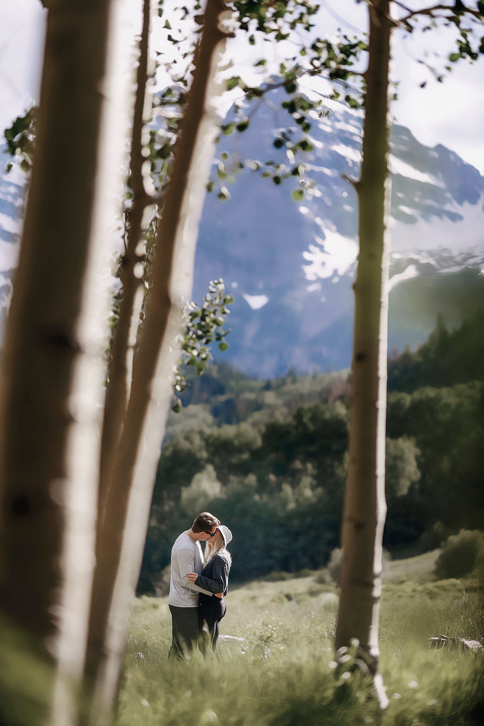 A young couple shares a sweet kiss as they celebrate their engagement in an aspen grove, in the Maroon Bells wilderness.