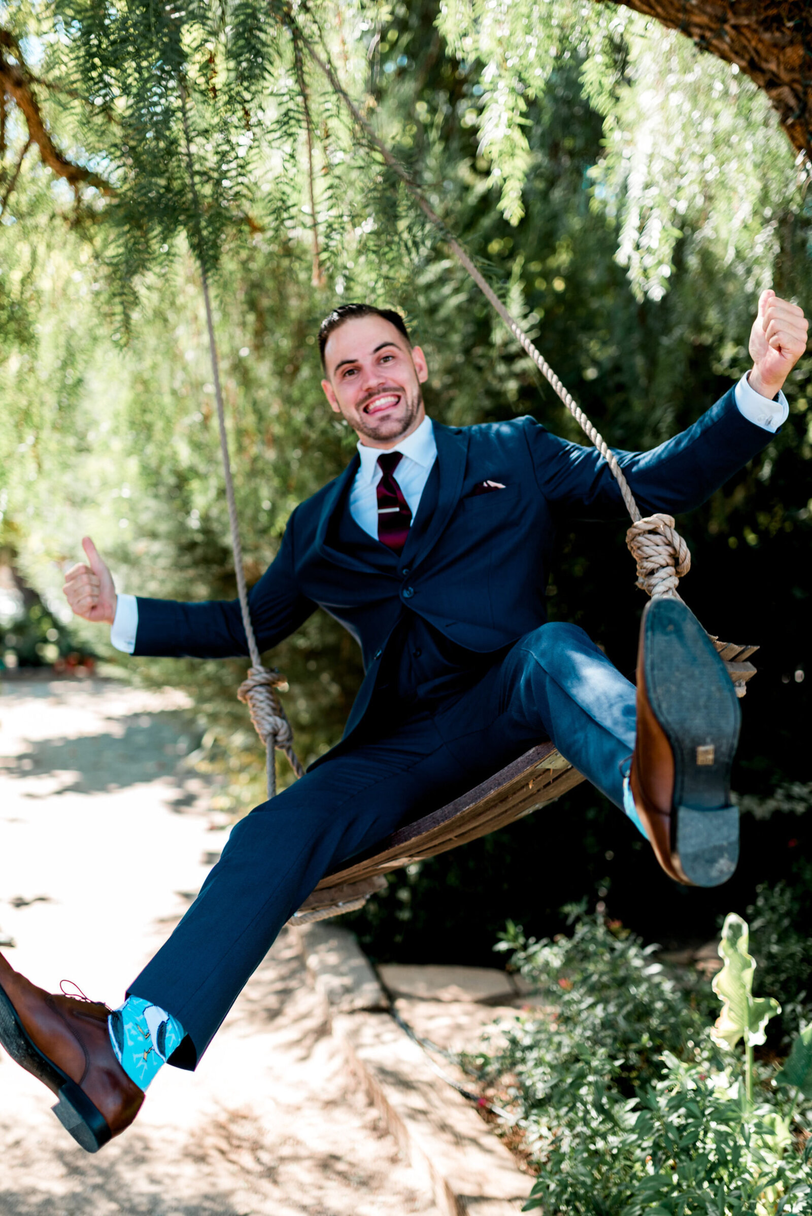 Groom on a swing, looking very excited with a big smile on his face, giving two thumbs up.